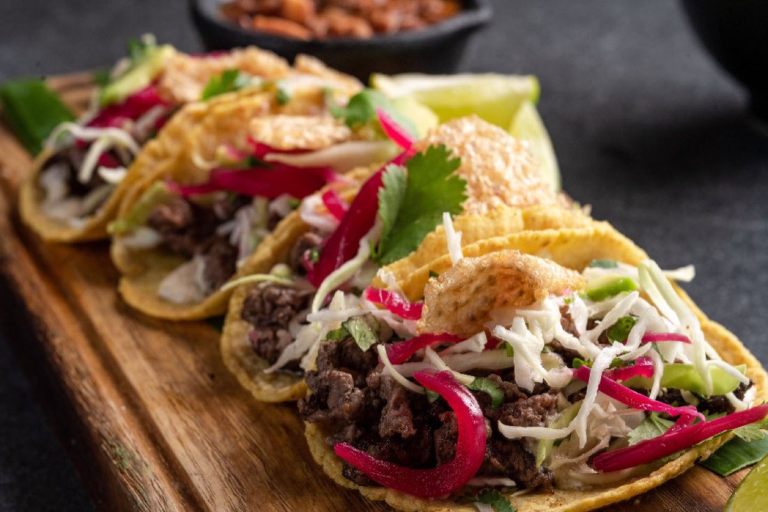 Tacos de carne con cebolla morada y col sobre tabla