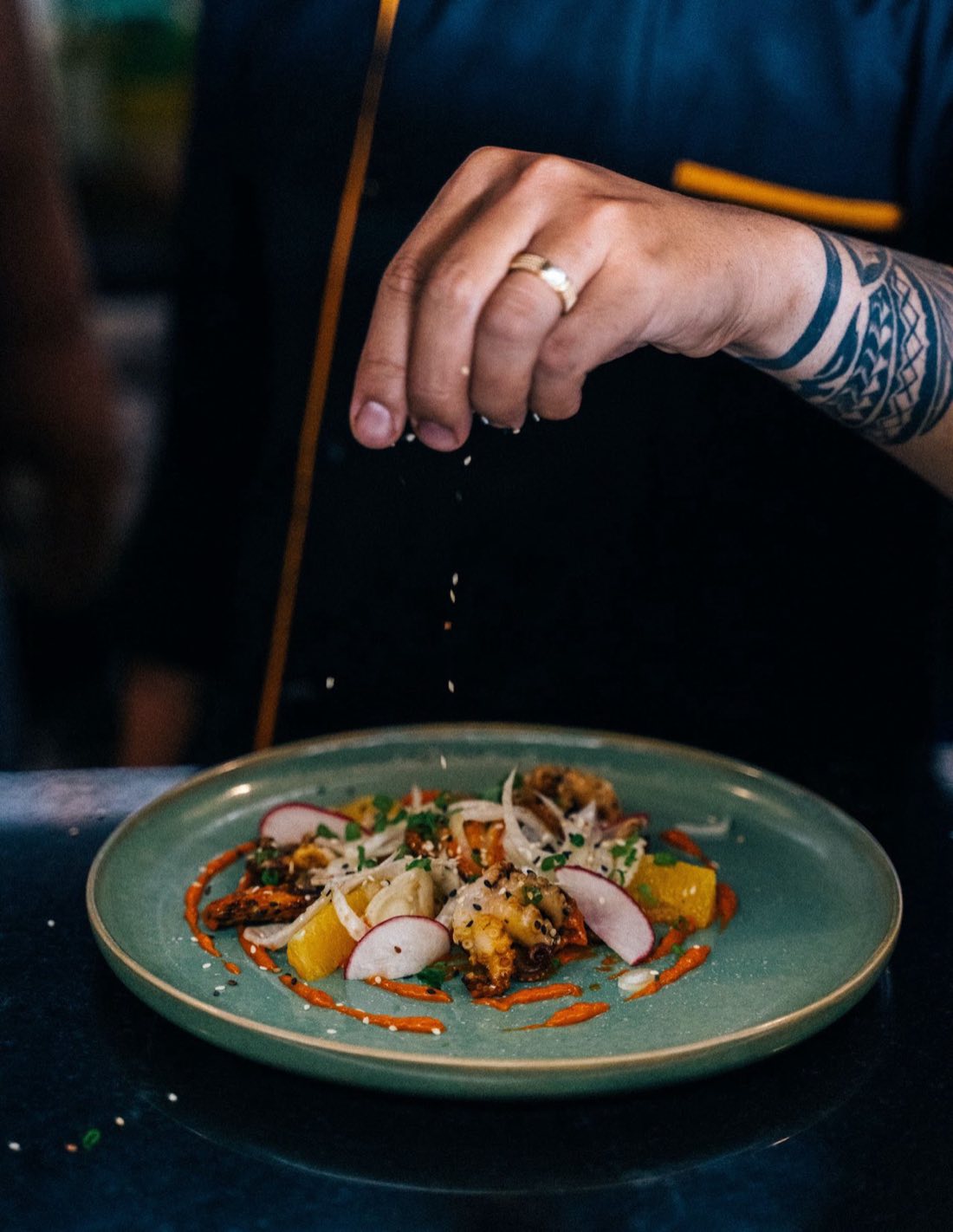 Chef espolvorea ajonjolí sobre un pulpo emplatado