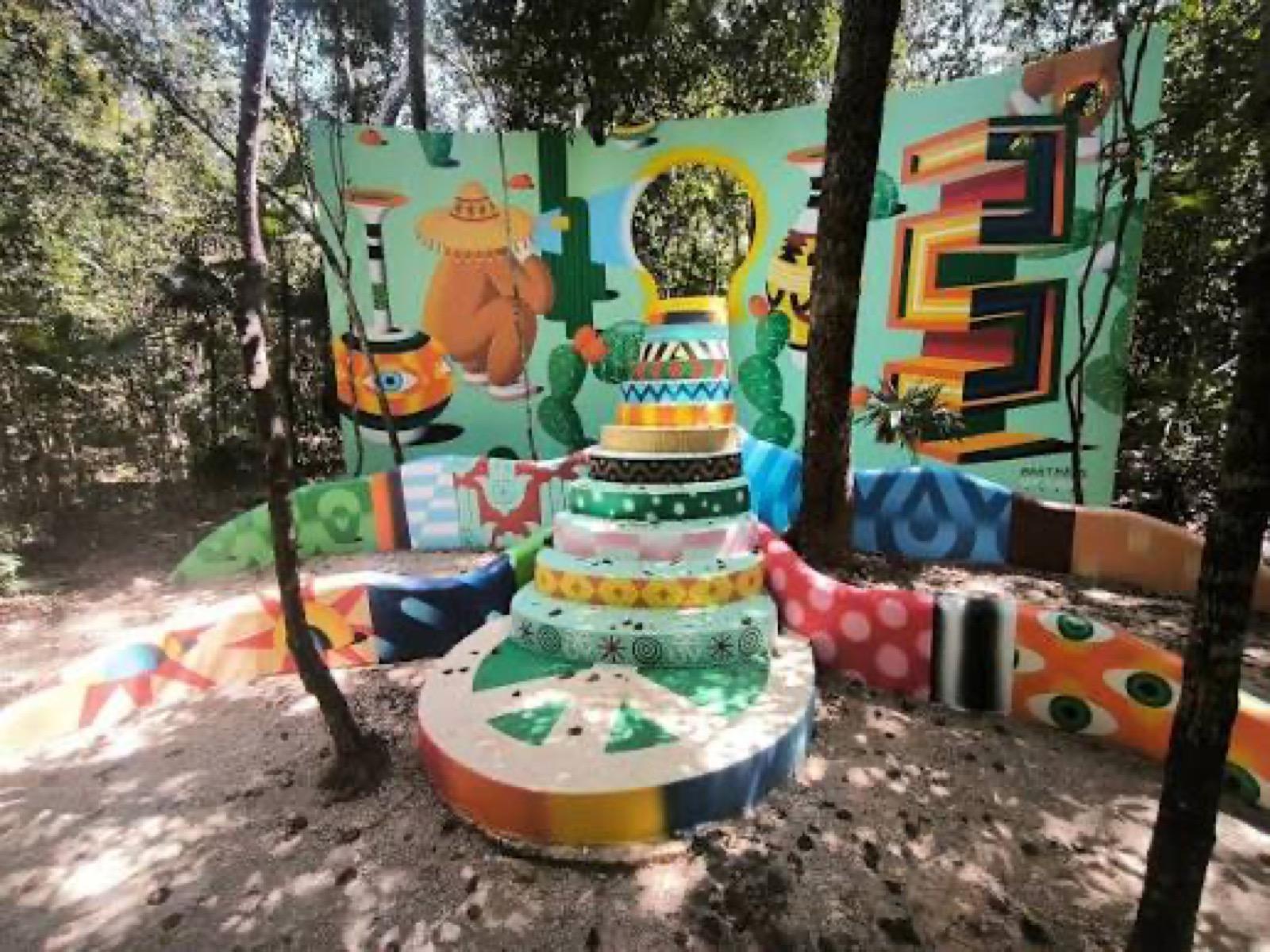 A hand-painted open-air tunnel installation, its curved mosaic walls covered with figures.