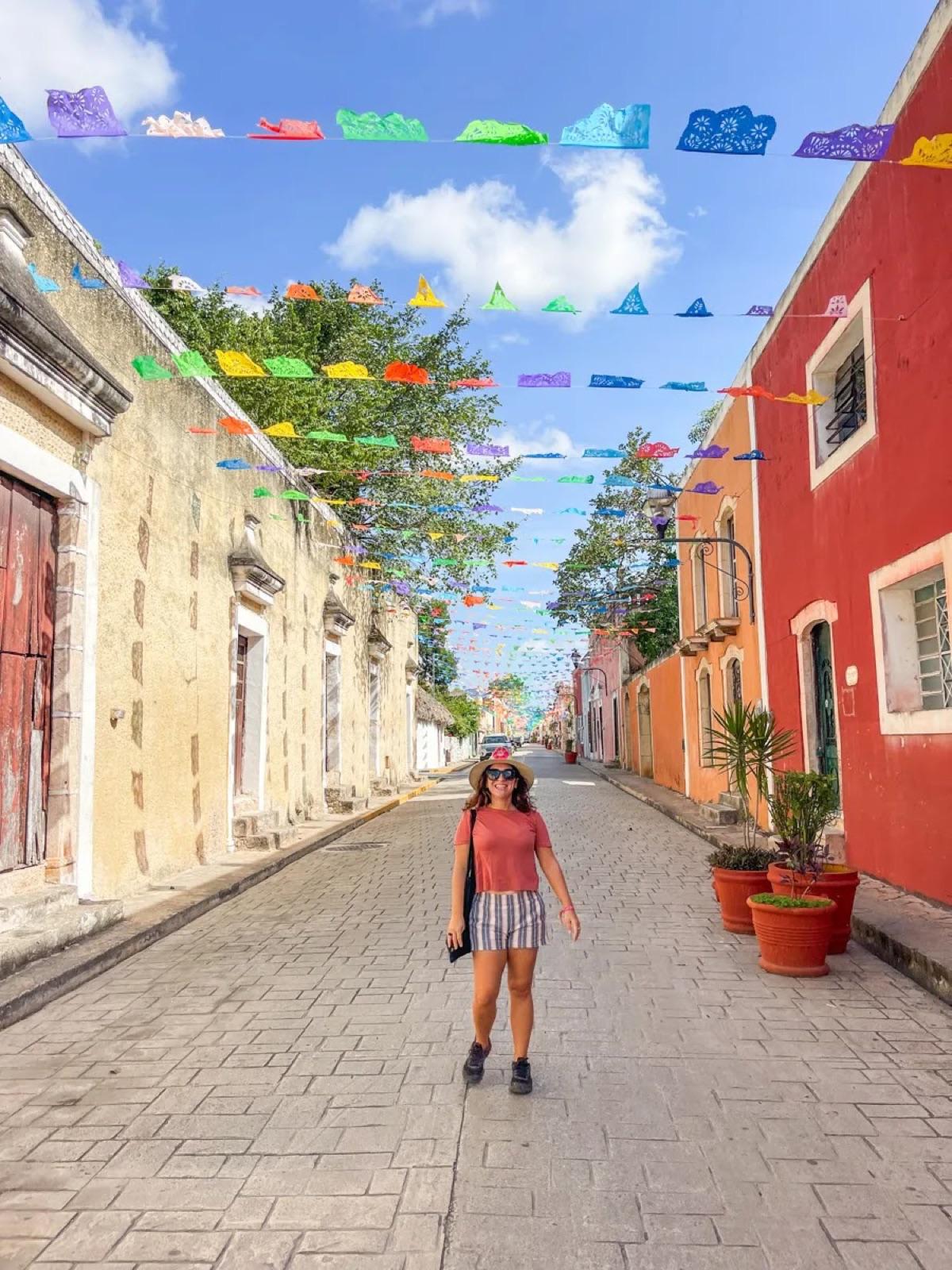 Una colorida calle colonial de Valladolid decorada con papel picado sobre fachadas en tonos pastel