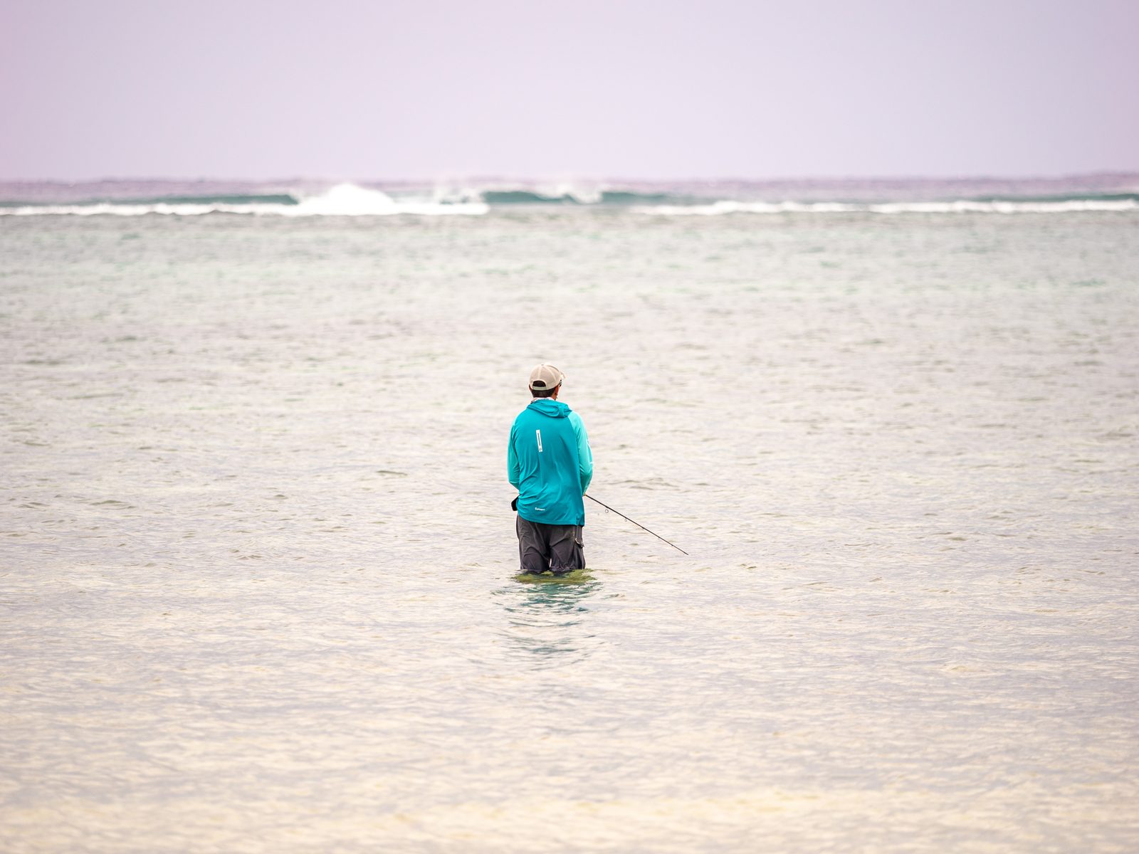 Un pescador con el agua a las rodillas en un flat claro