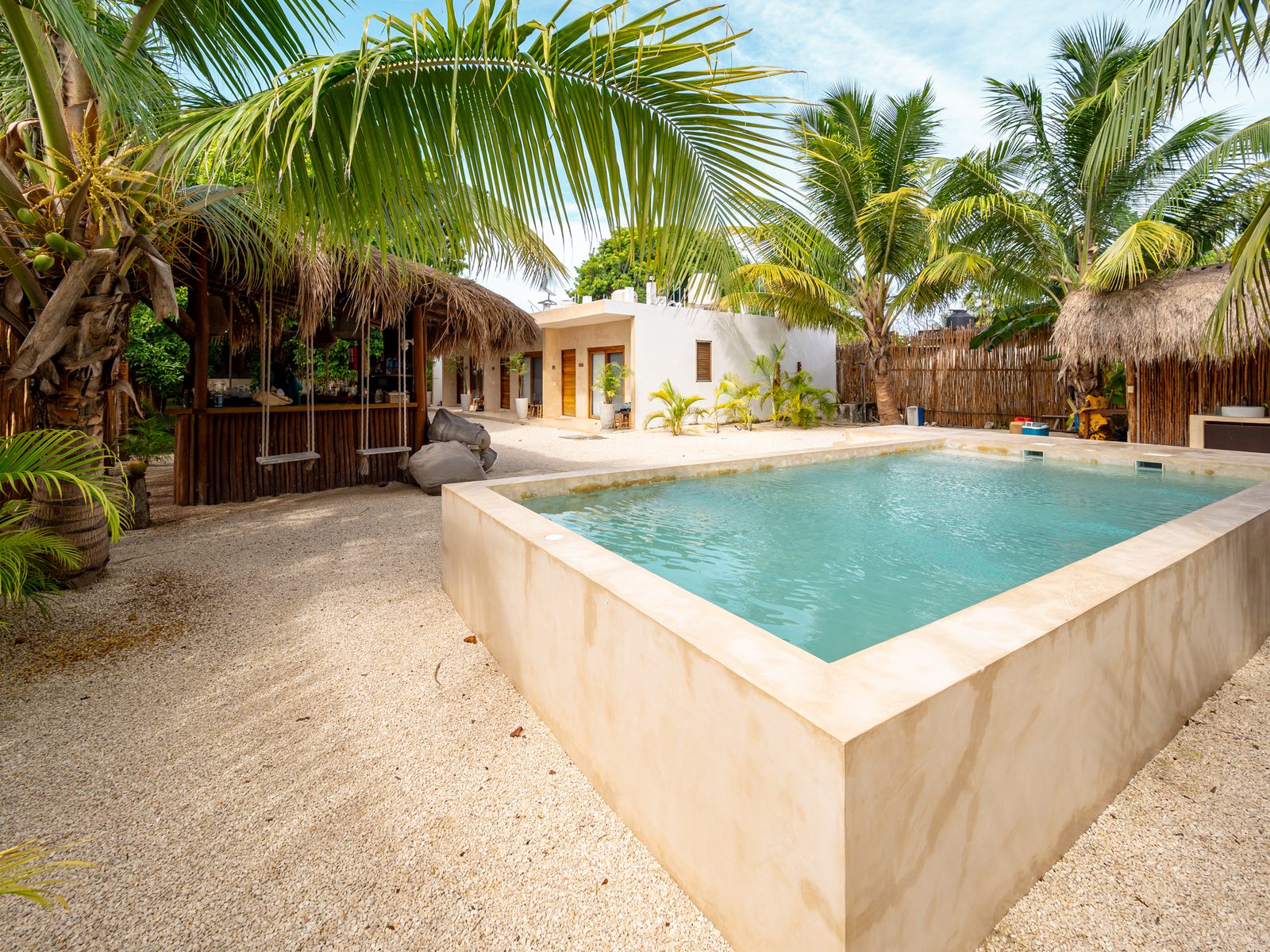 La alberca del lodge entre palmeras y techos de palapa