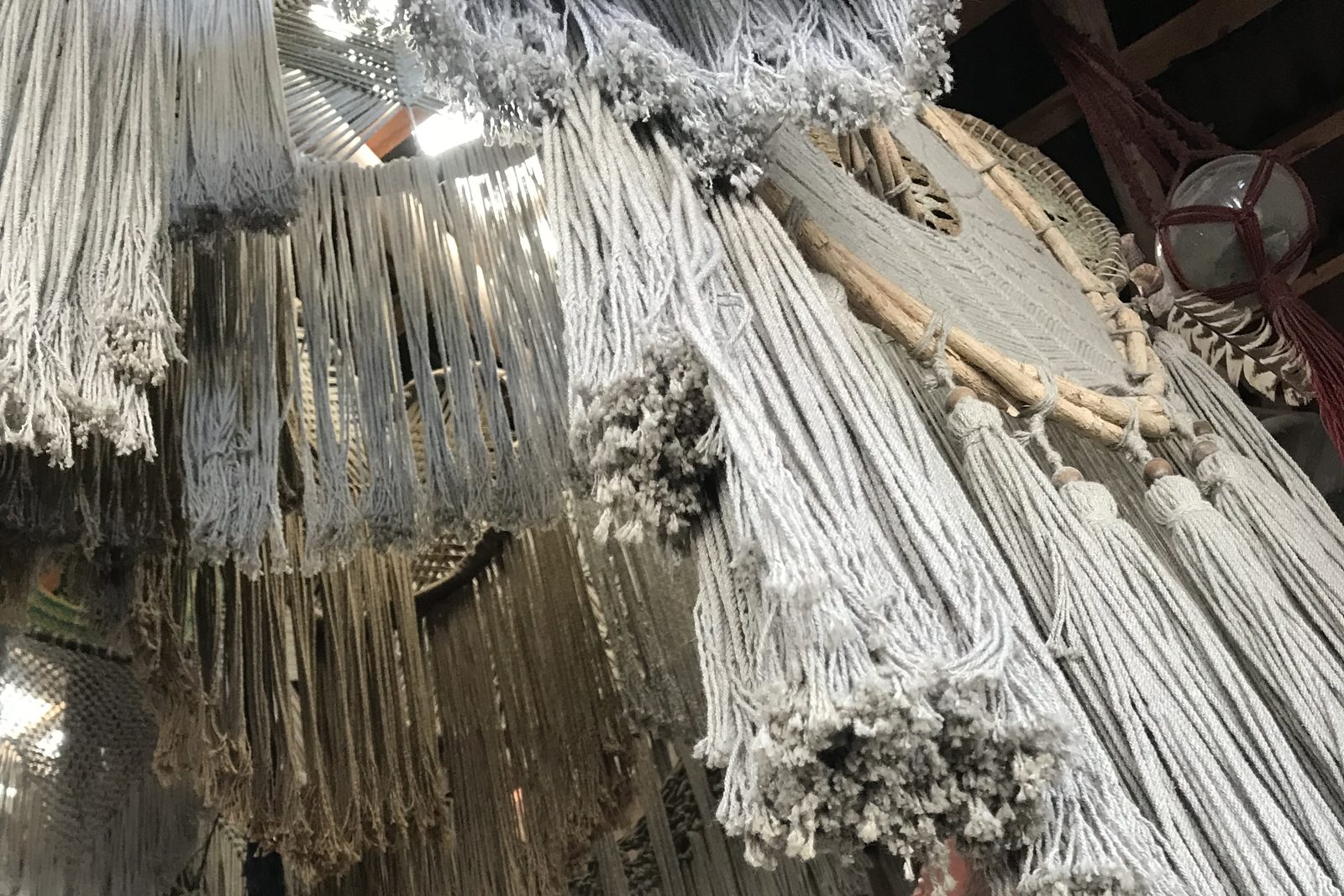Piezas de macramé y atrapasueños colgando del techo de una tienda artesanal