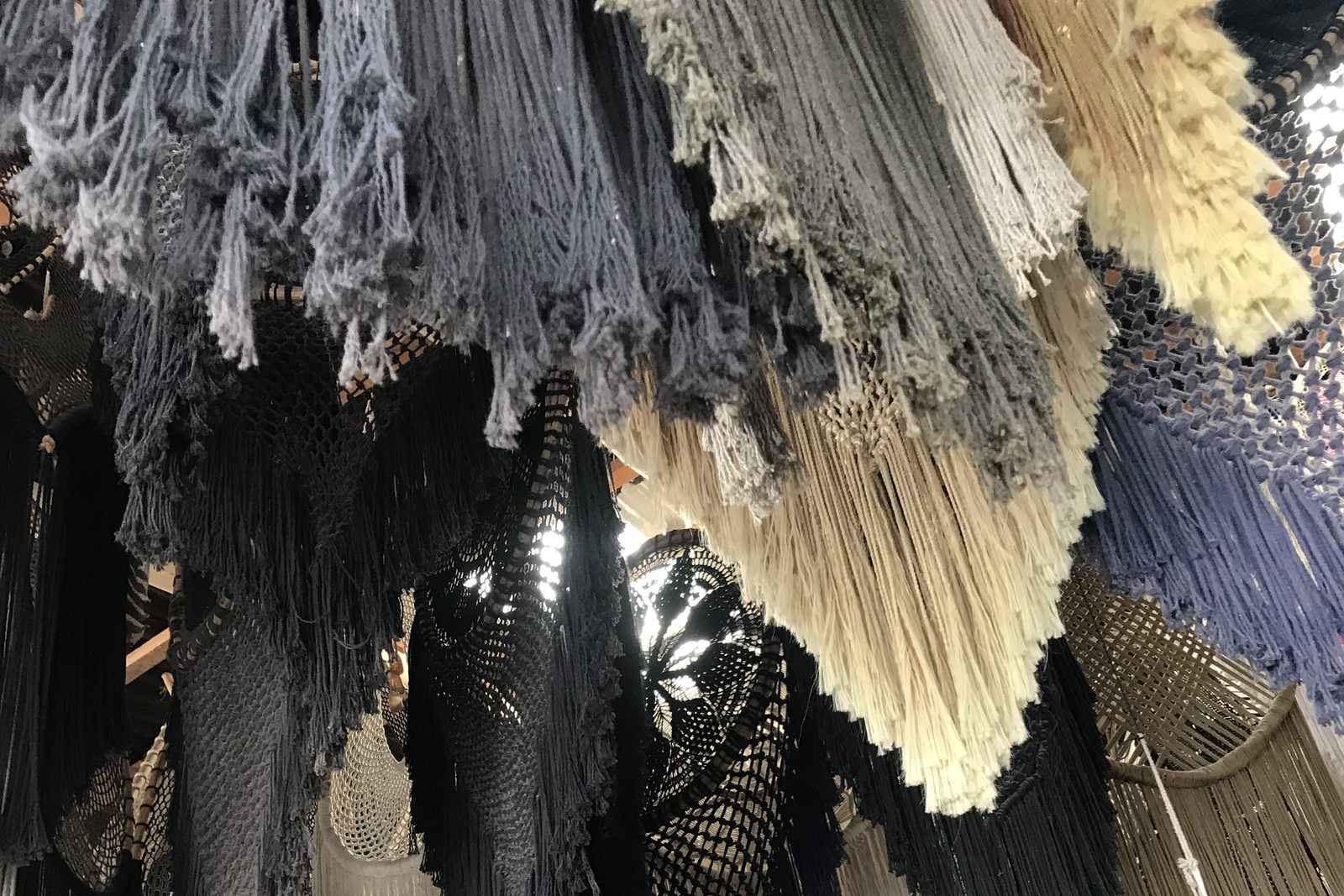 Macramé oscuro y flecos color crema colgando uno junto a otro