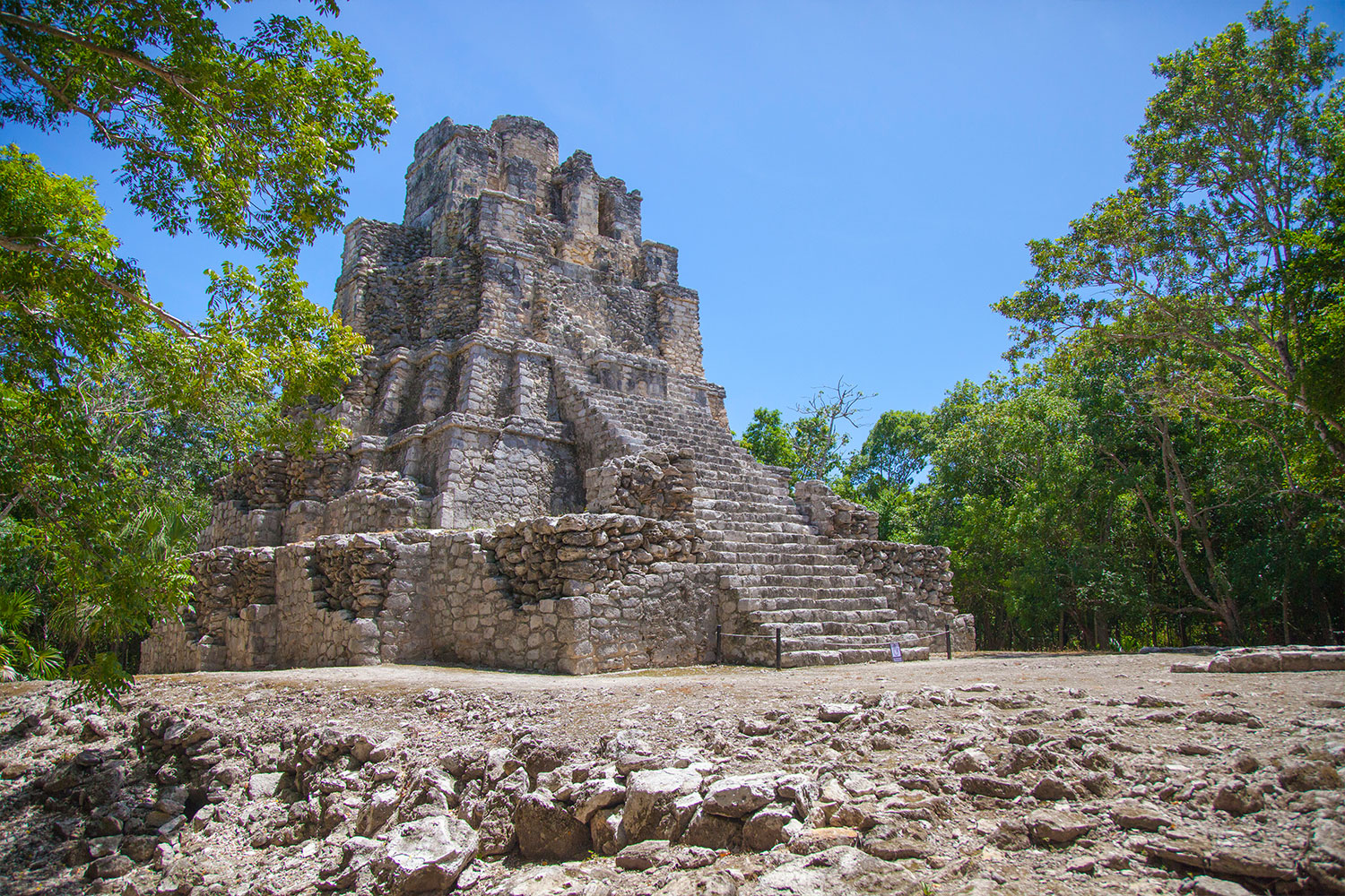 El Castillo escalonado de piedra de la zona arqueológica de Muyil bajo un cielo azul.