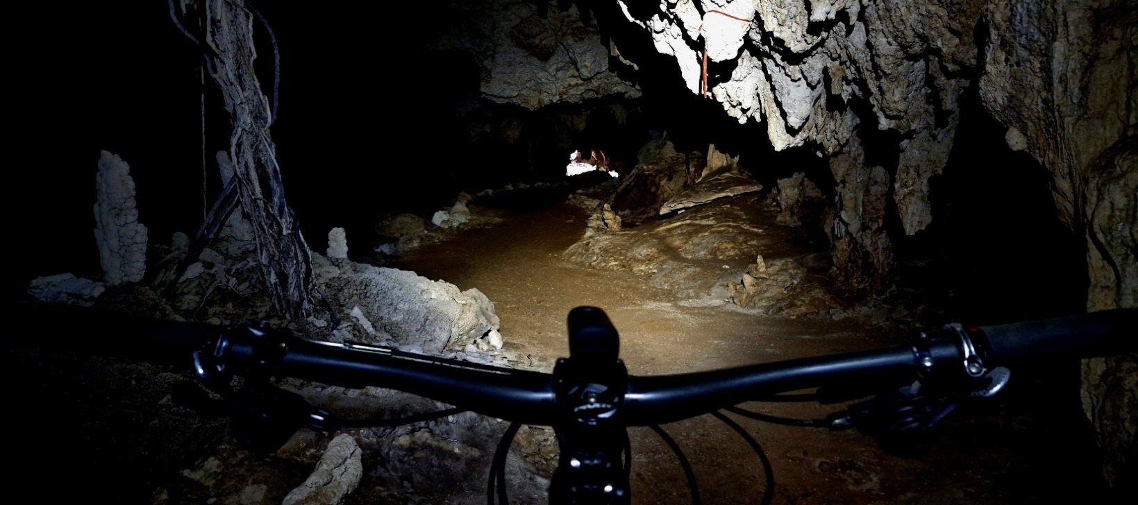 View over the handlebars and lamp inside a dark cave
