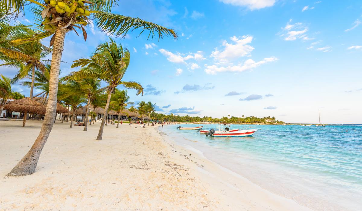White-sand beach and boats on the turquoise water of Akumal Bay.