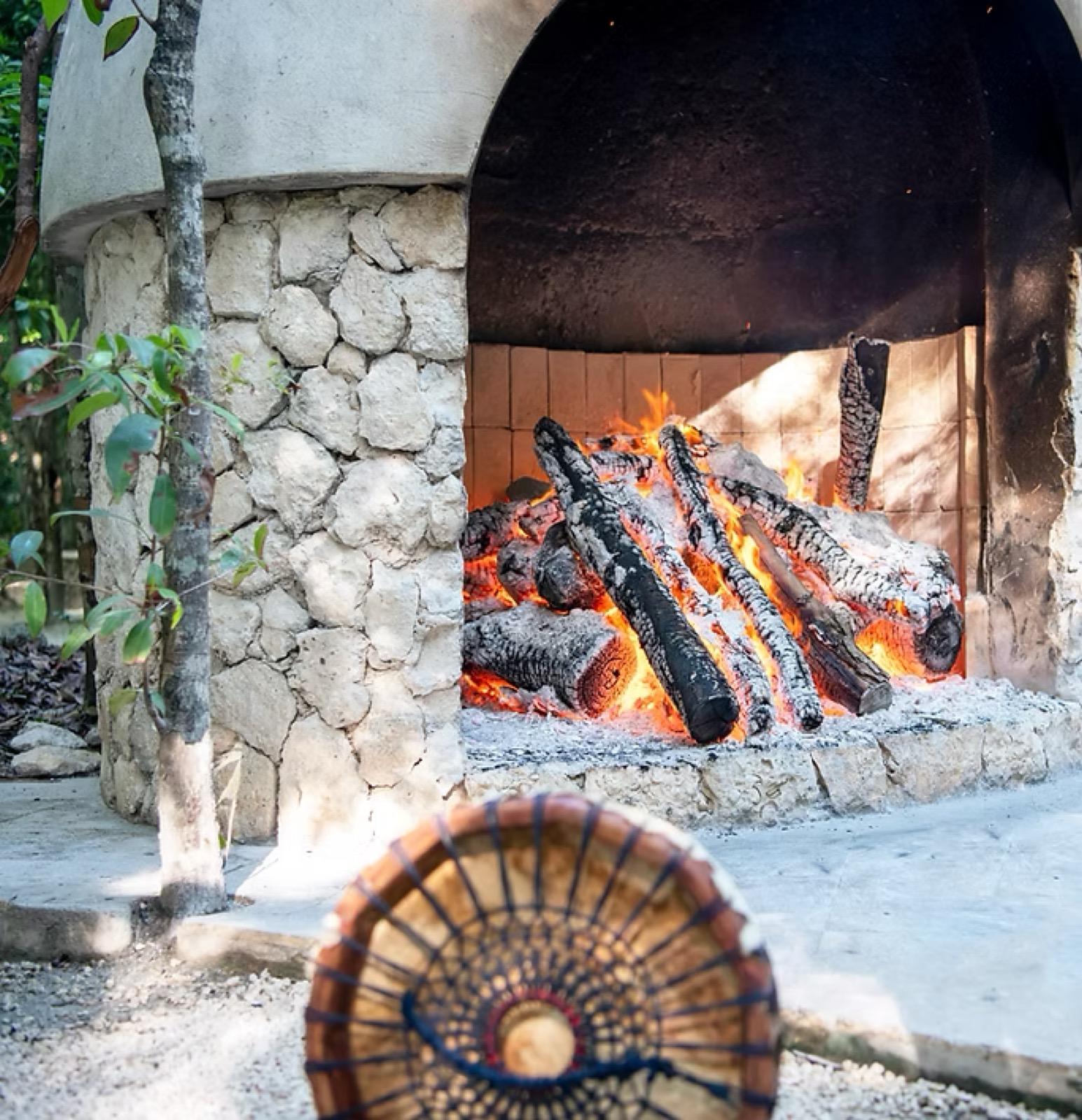 Un tambor ceremonial frente al fogón de piedra encendido de un temazcal en la selva.