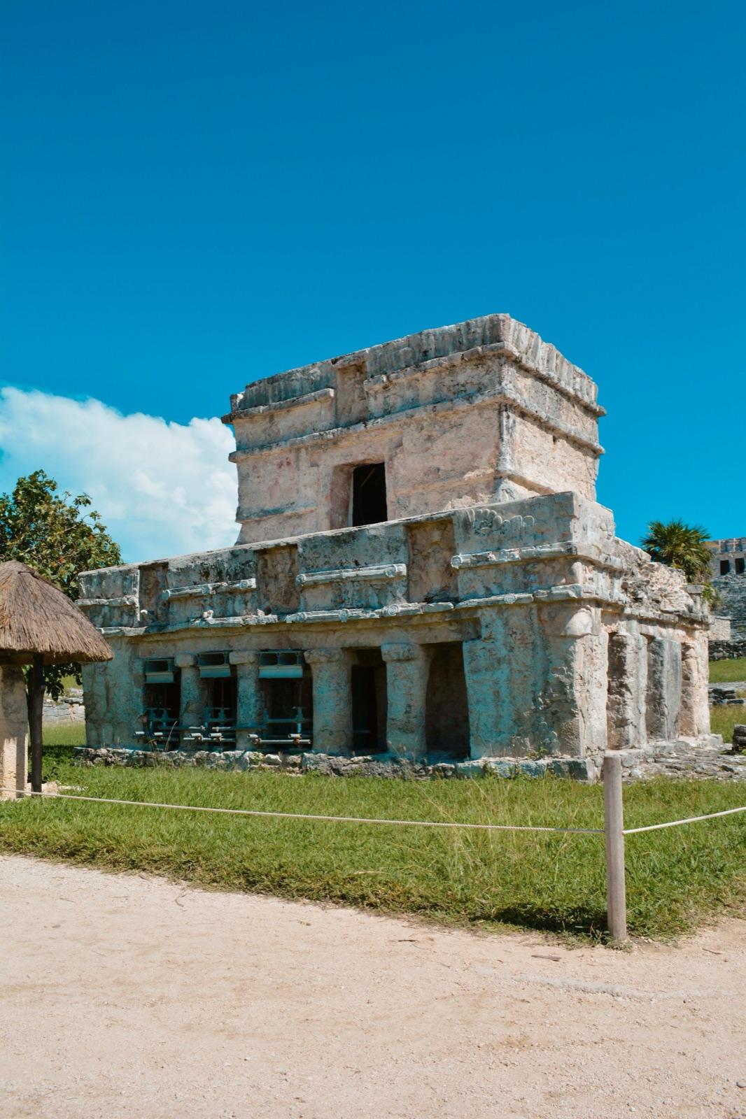A well-preserved two-tier stone Maya temple at the Tulum ruins against a deep blue sky