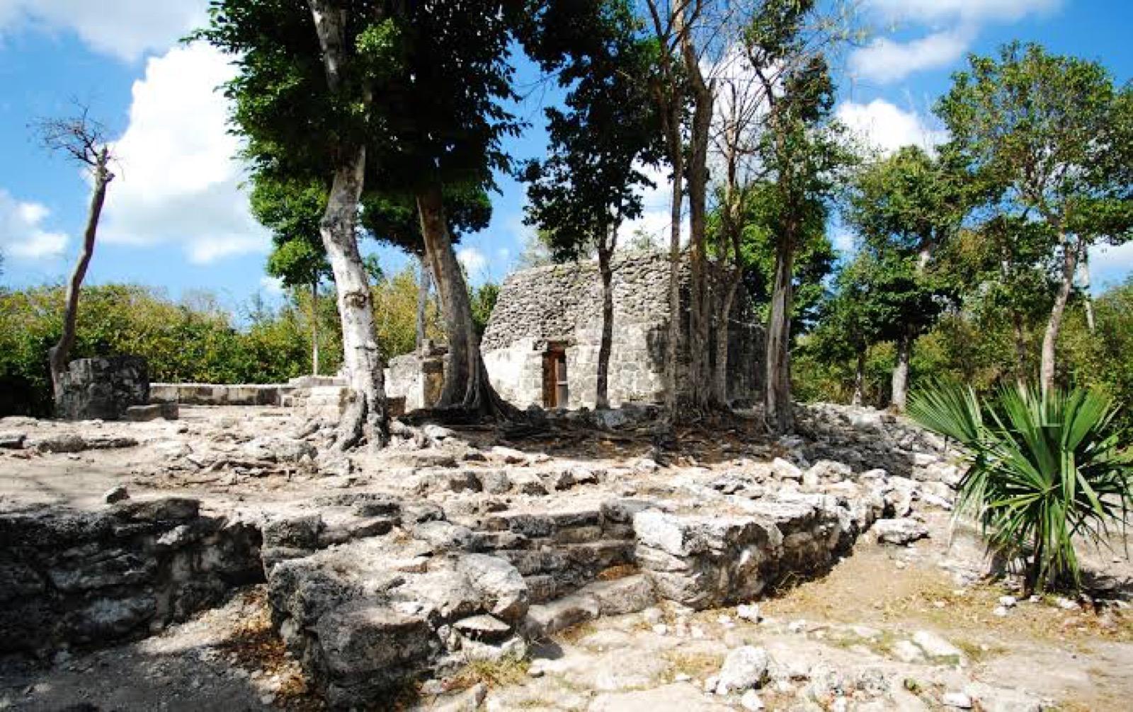 Weathered Maya ruins framed by jungle greenery under a blue sky at Xel-Há.