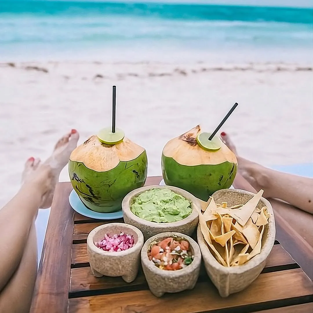 Fresh coconuts and ceviche served on a table facing the sea
