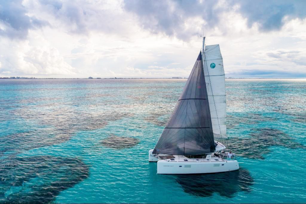 The catamaran under full sail over the reef