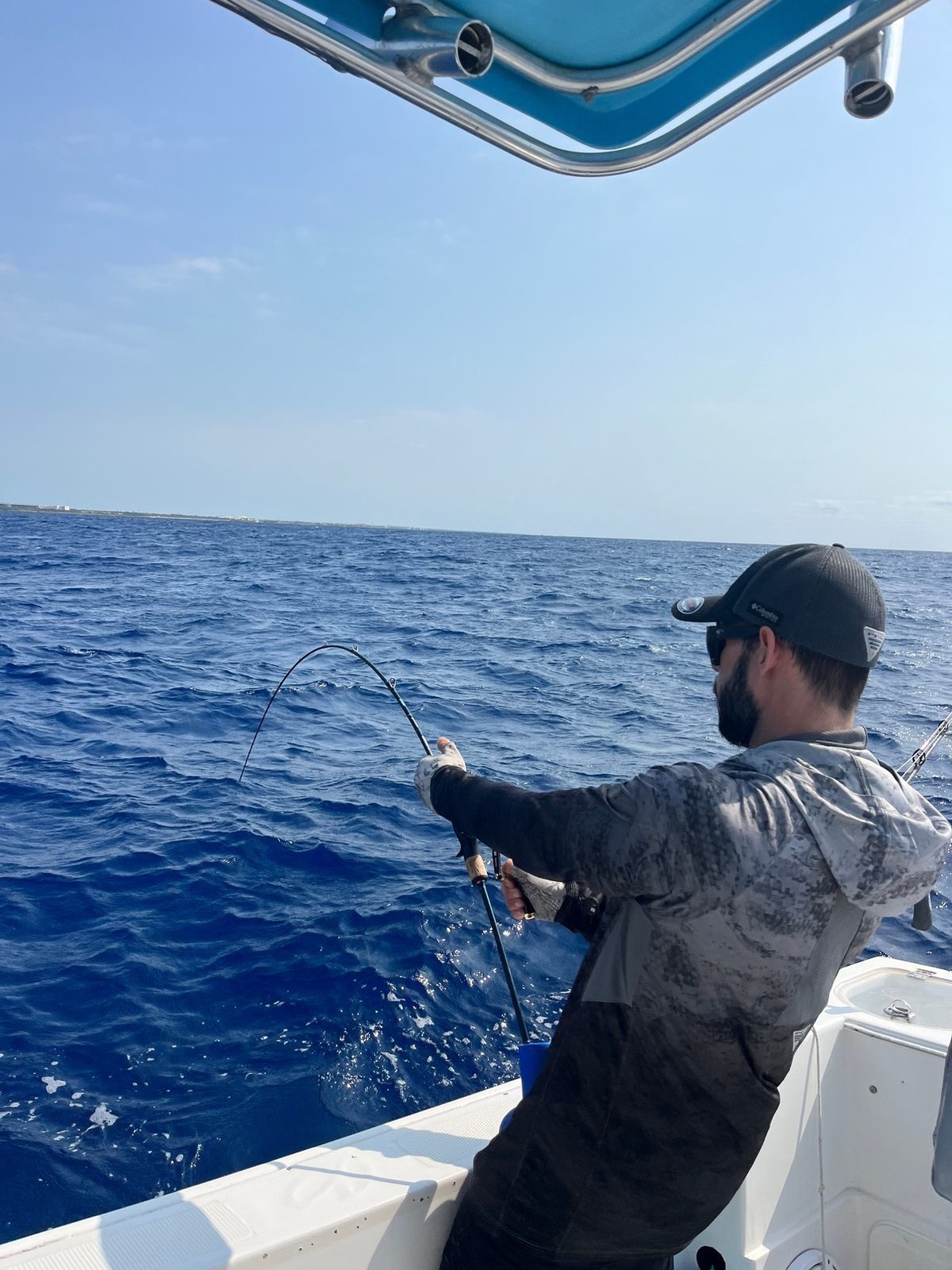 An angler working a fish from the side of the boat