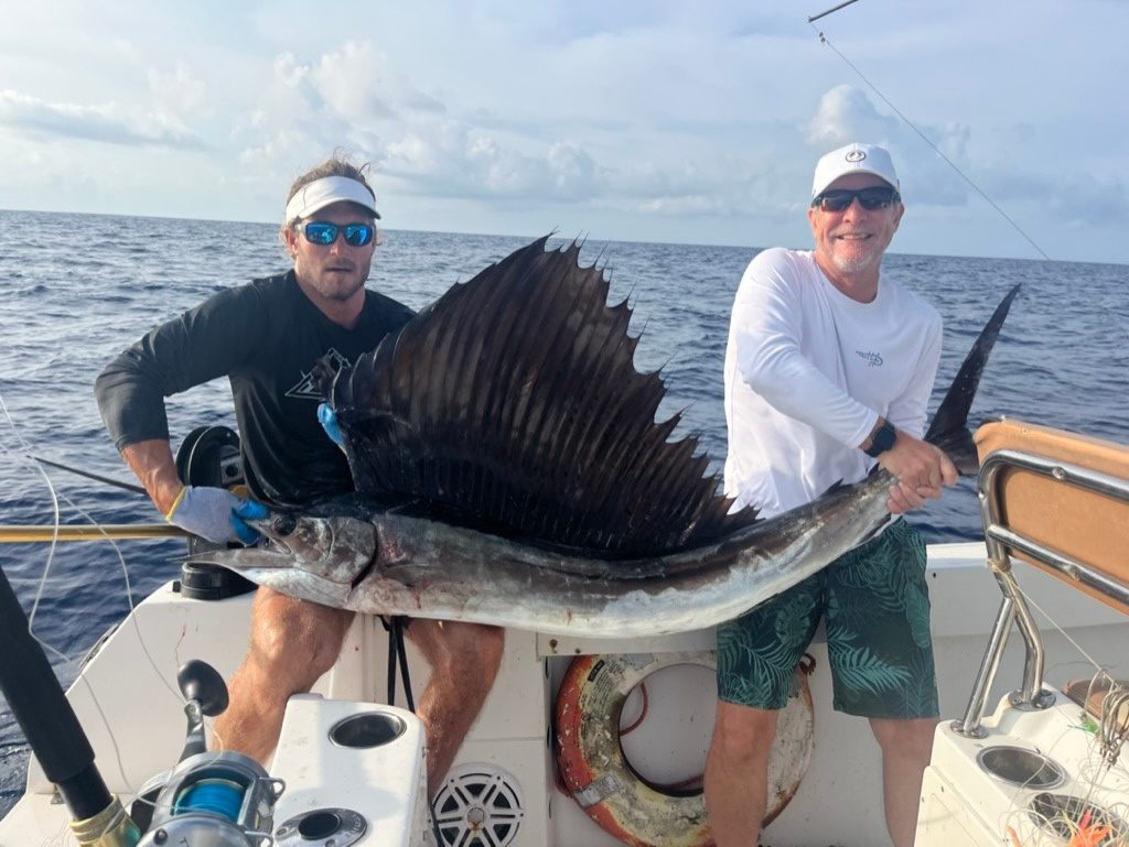 Two anglers holding a sailfish aboard