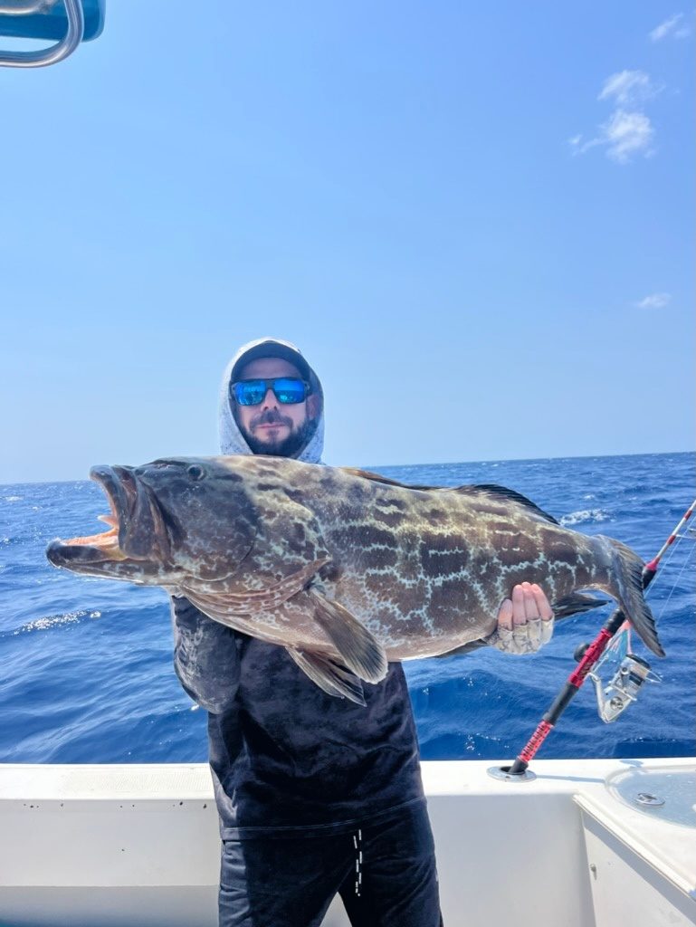 A grouper held up over open water