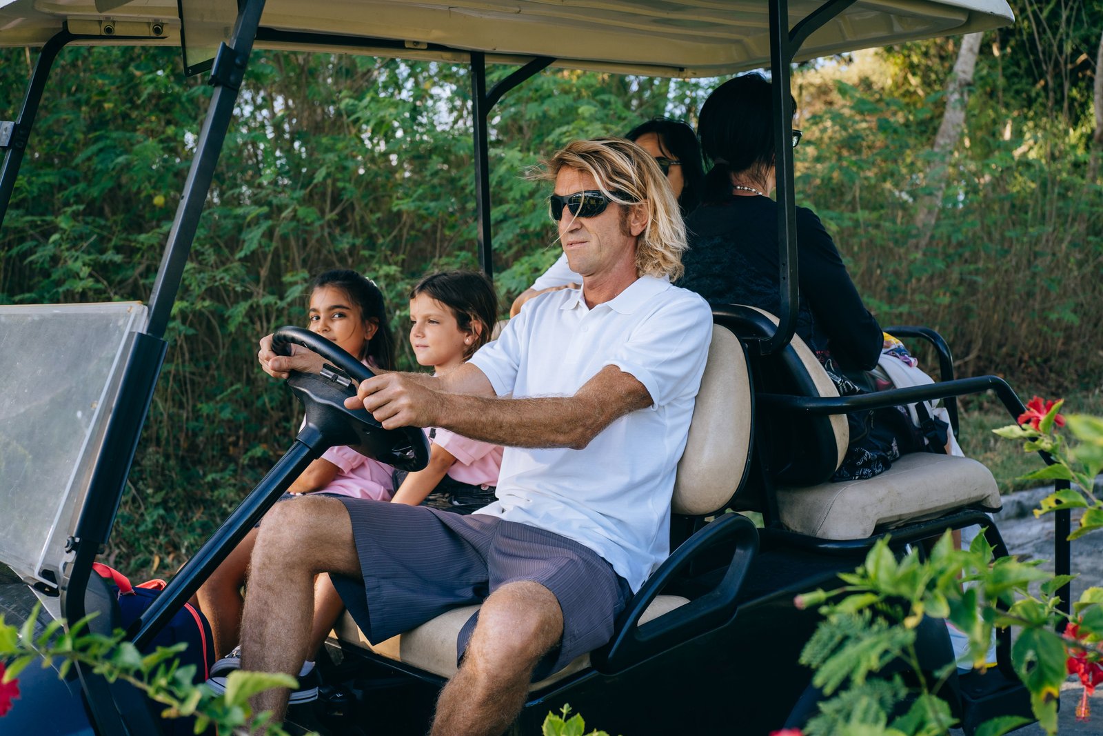 A family crossing the village by golf cart, children riding up front