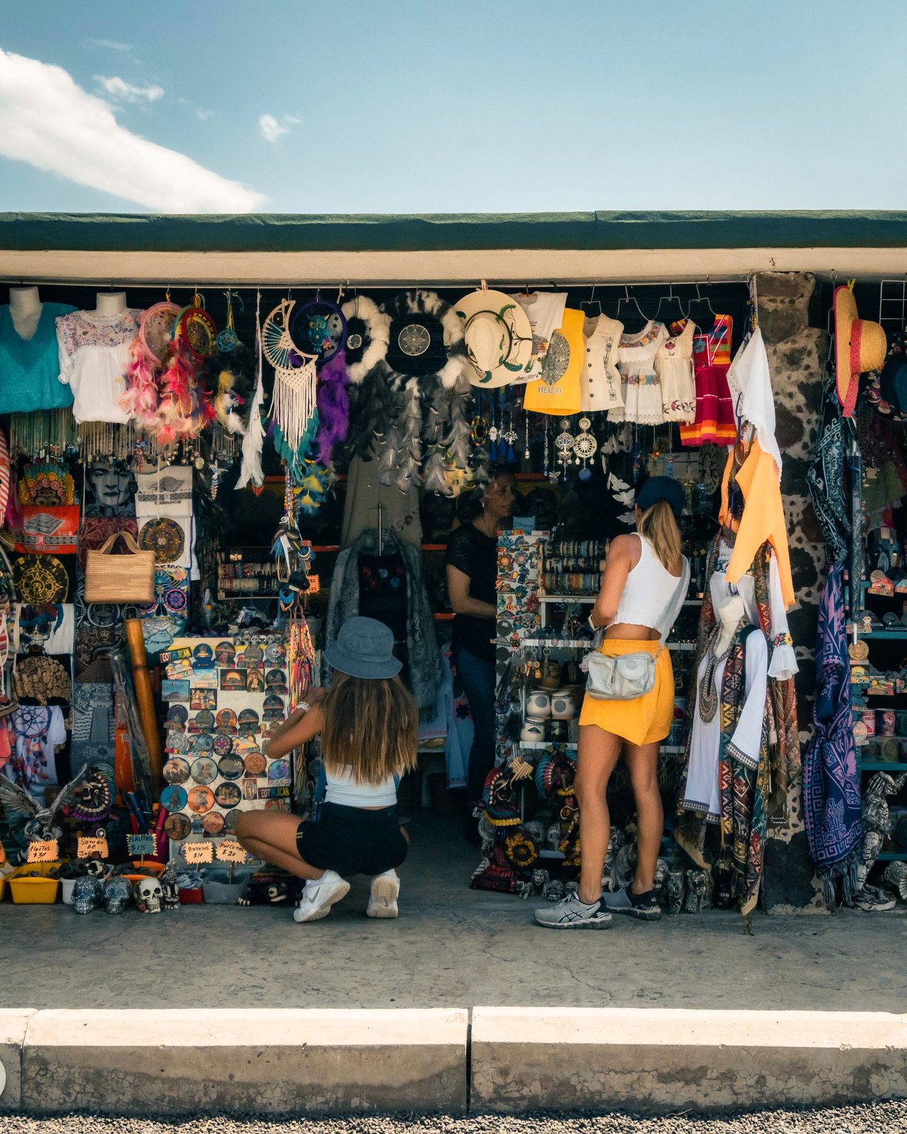 Dos viajeras recorren una tienda de recuerdos abierta a la calle