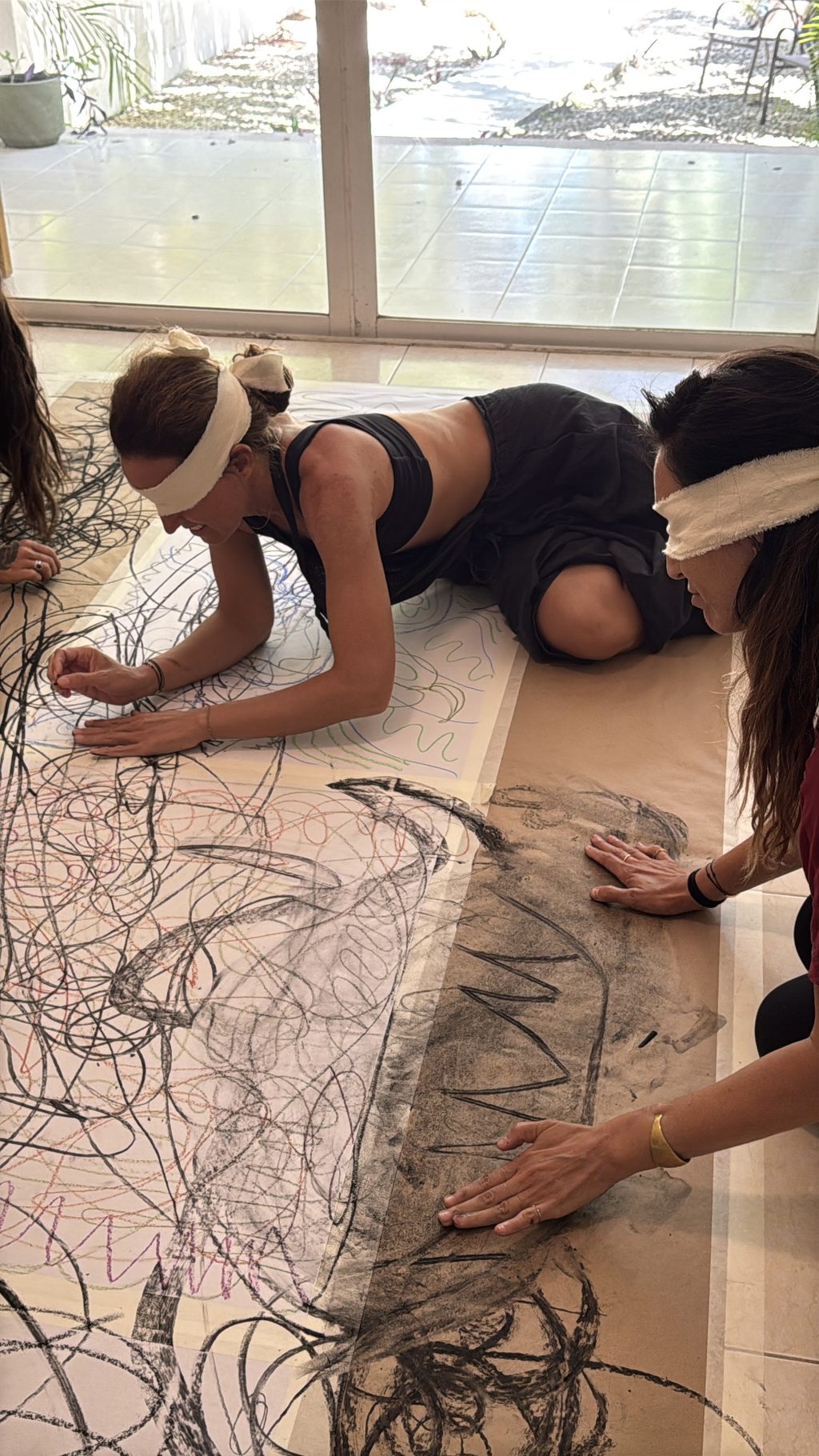 A group drawing with charcoal on a long sheet on the floor