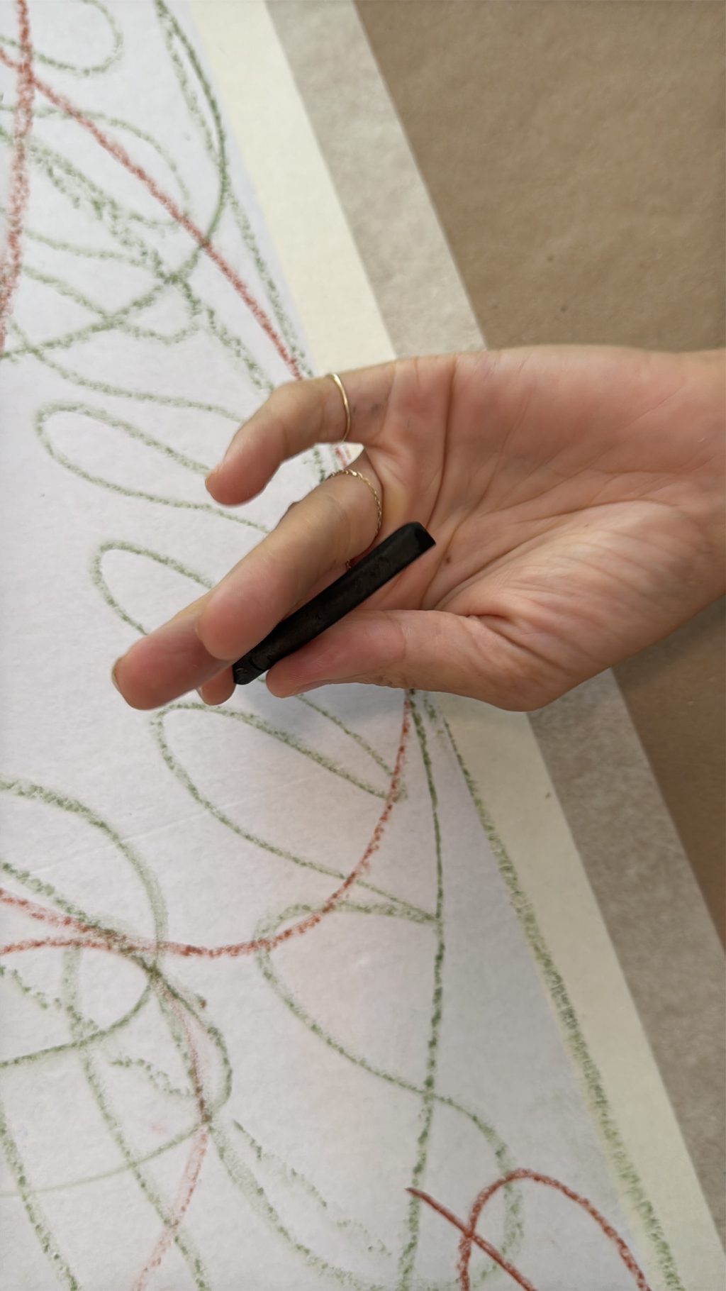 A hand holding charcoal over the paper