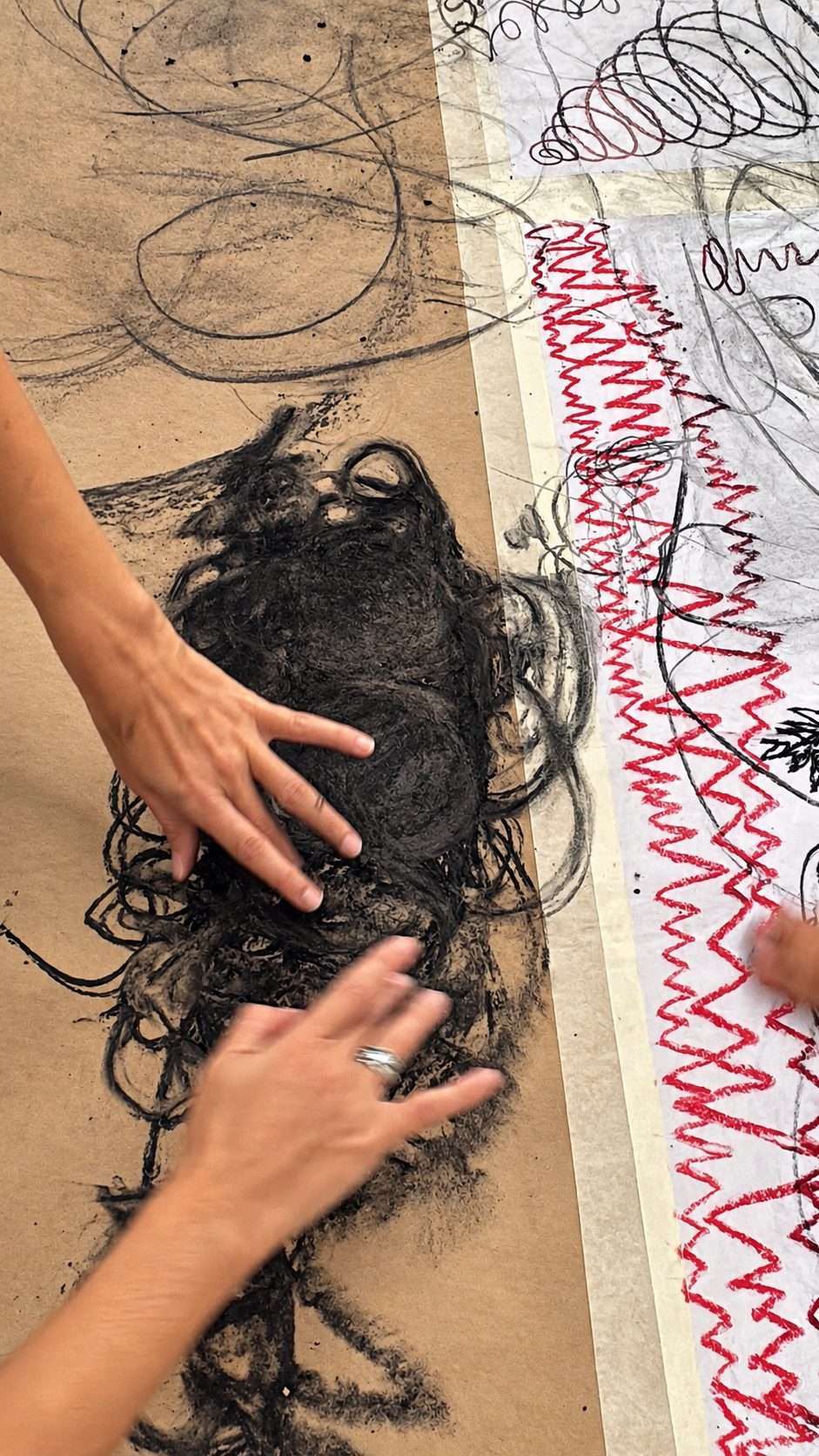 Hands working the charcoal on the paper