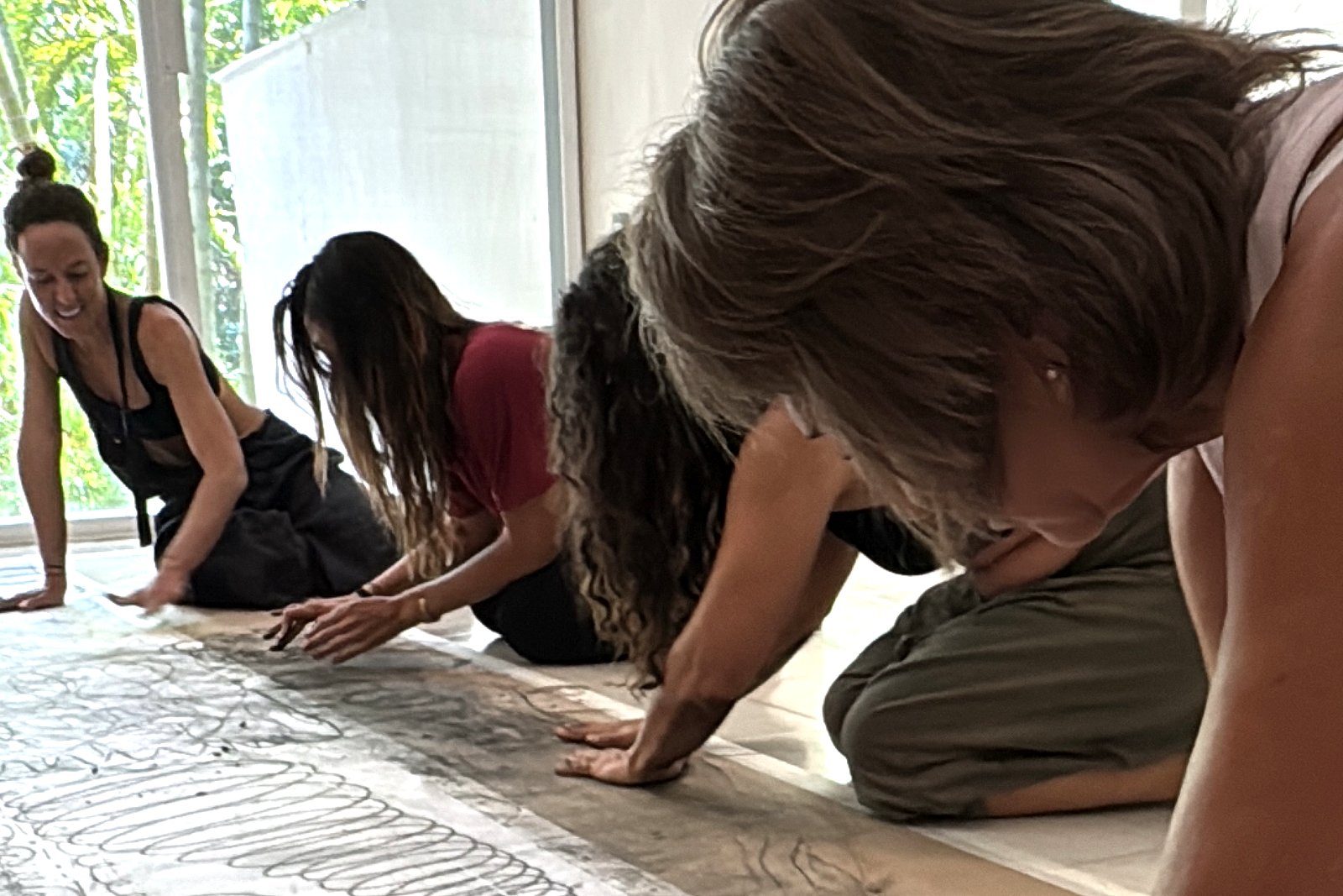 Three guests drawing with their hands on a long sheet of paper on the floor