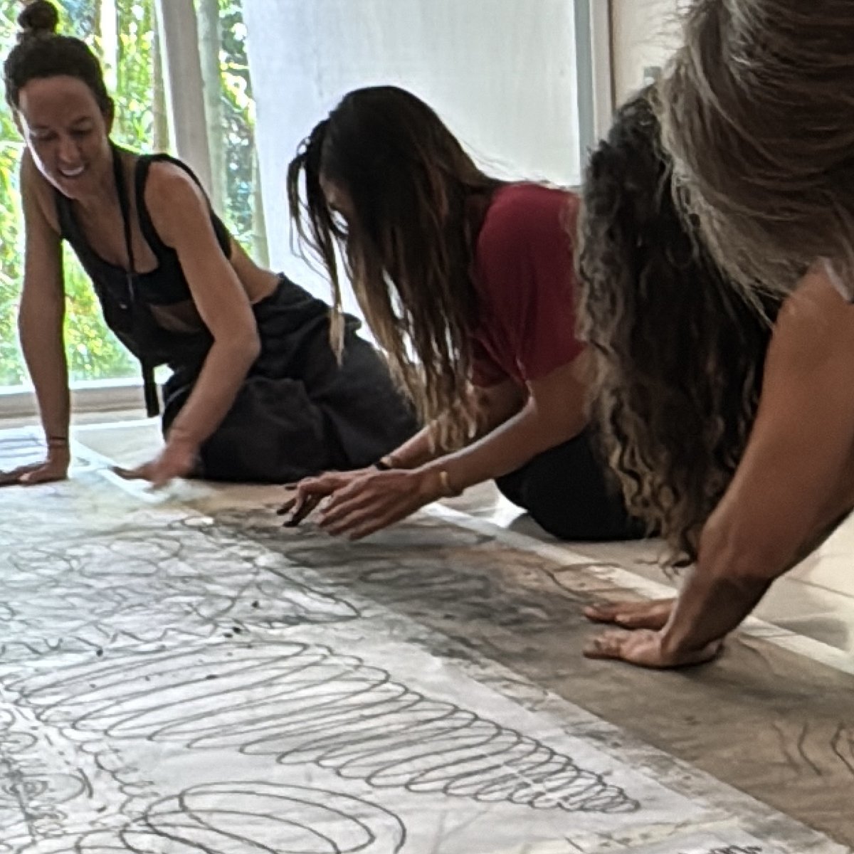 Three guests drawing with their hands on a long sheet of paper on the floor