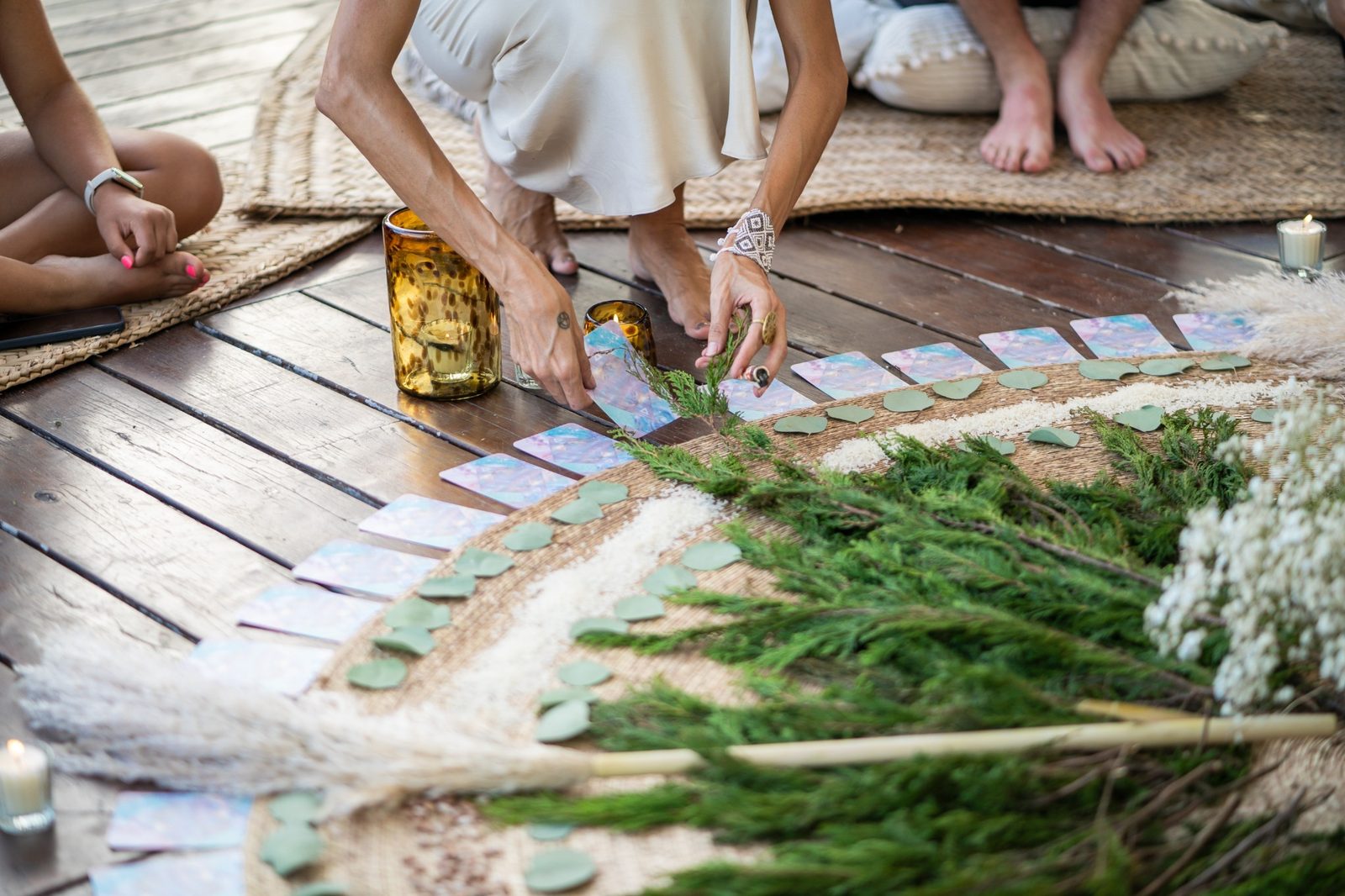 Hands placing written intentions on an altar of greenery and candles