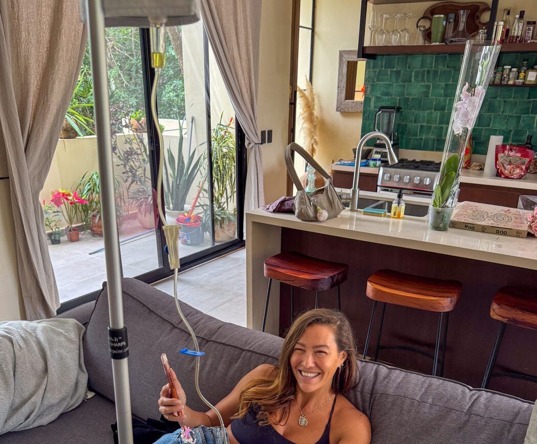 A guest smiling on the sofa of her vacation rental with an IV drip beside her