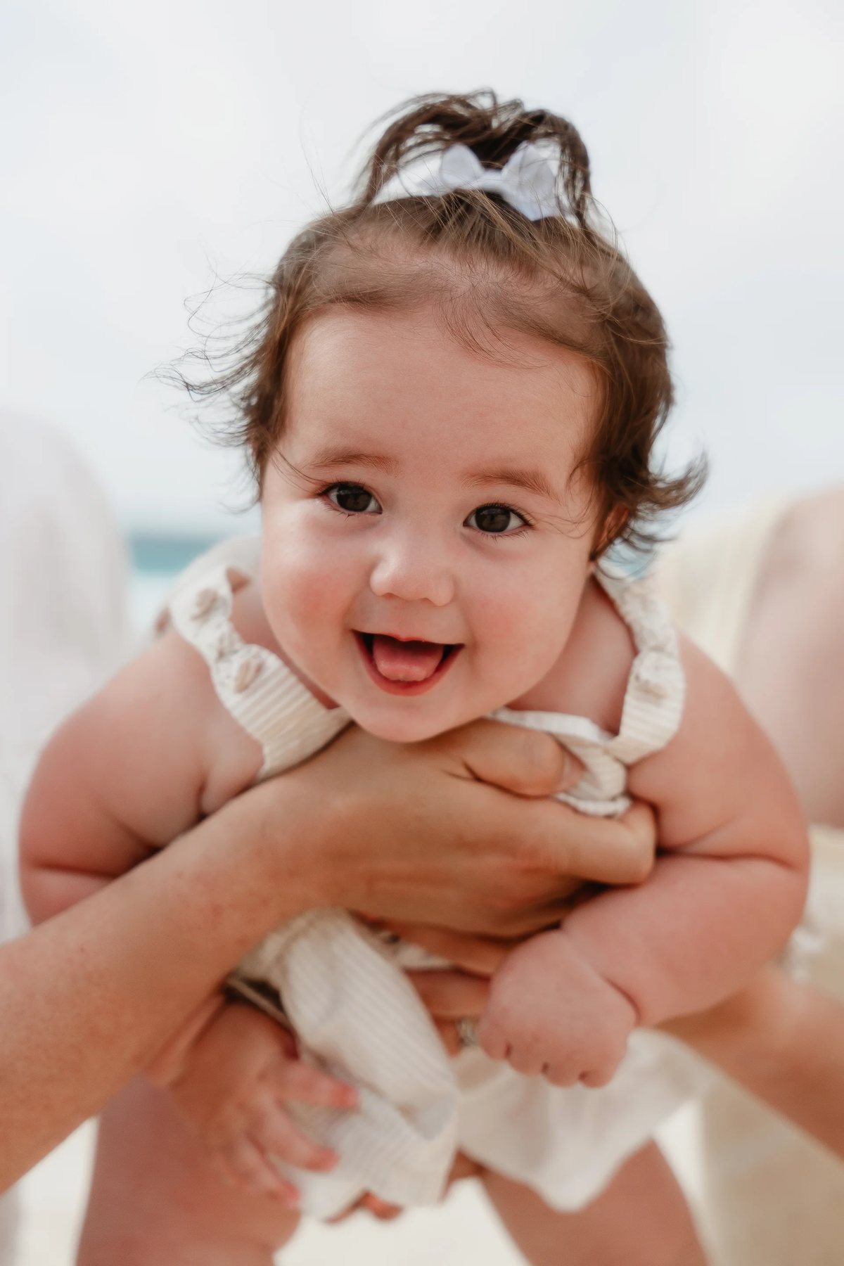 A smiling baby lifted up on the beach