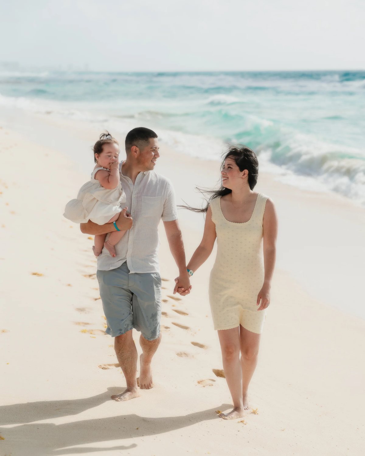 Parents and their baby walking along the shore