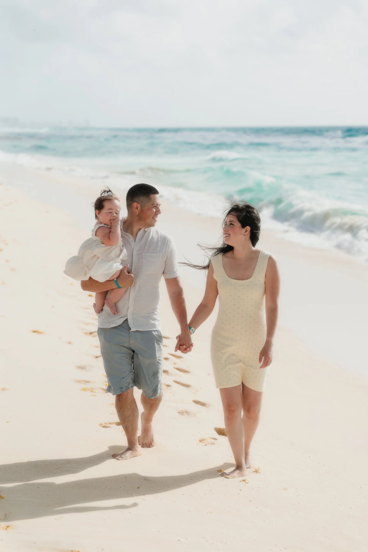 Parents and their baby walking along the shore