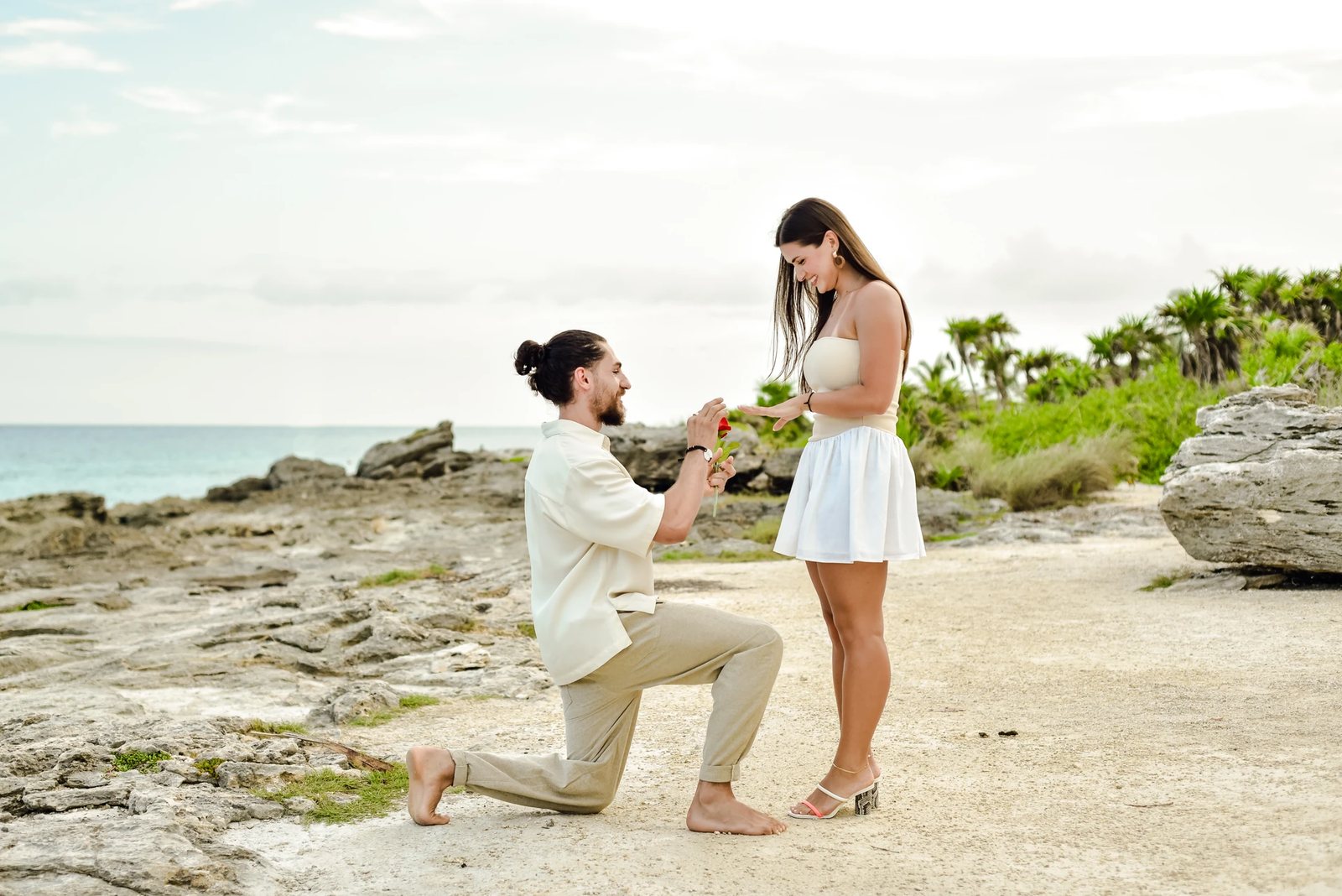 A marriage proposal on the rocky Caribbean coast, he kneels with the ring
