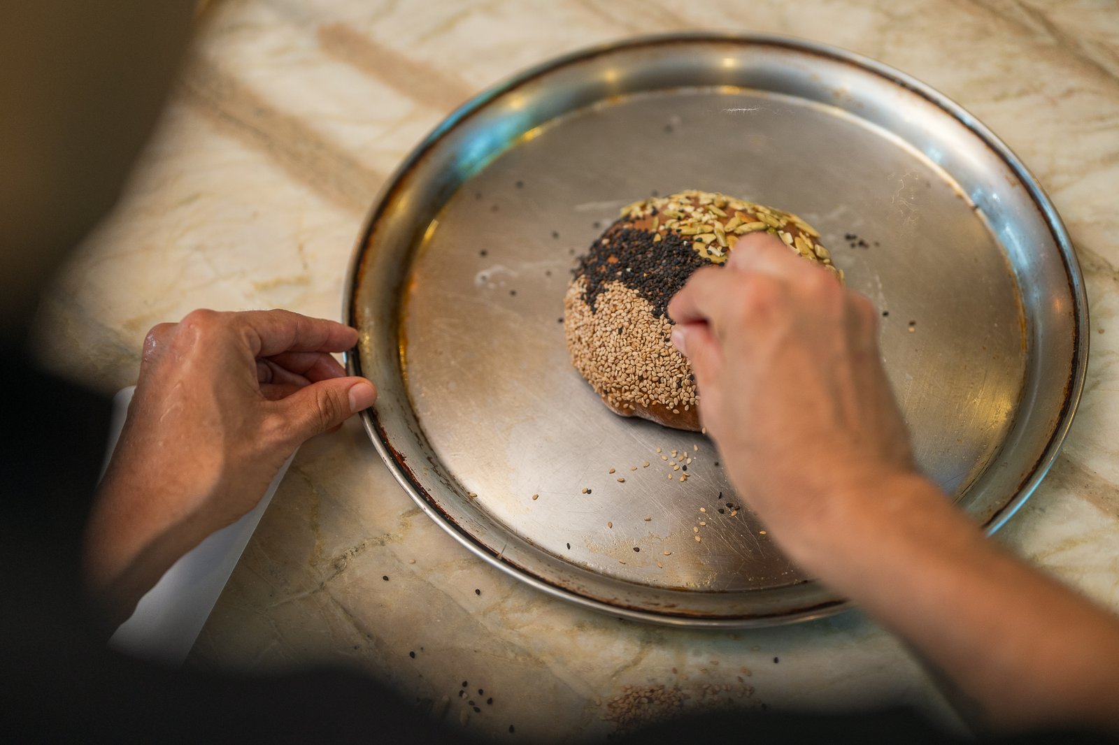 The chef finishes a dish with toasted seeds
