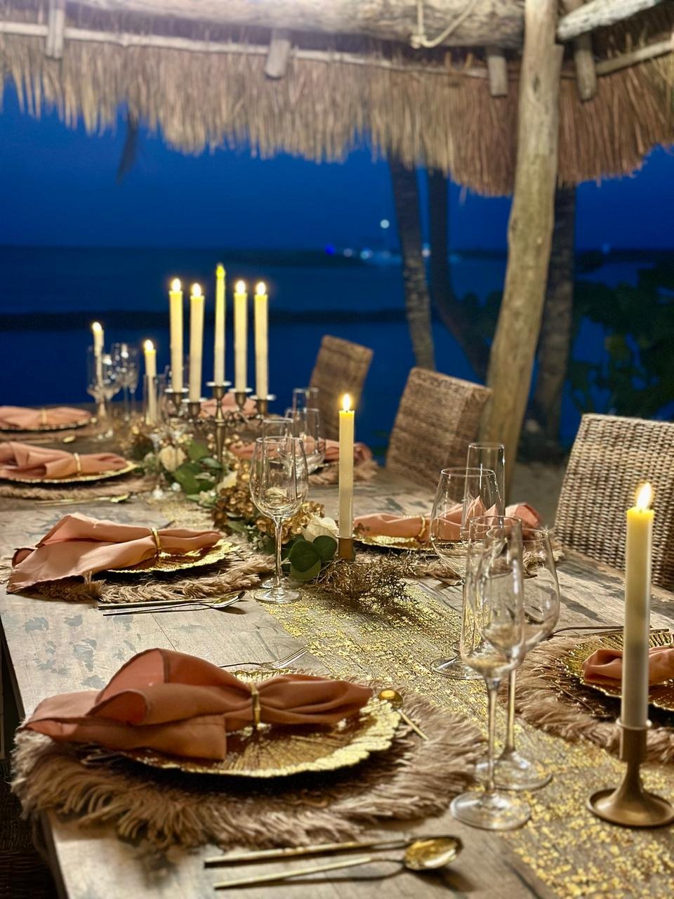 A candlelit table set for a private dinner by the sea