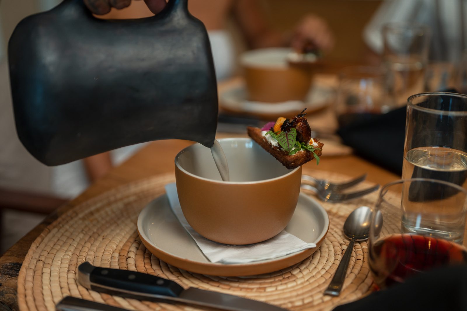 The chef finishes a dish at the villa table, poured straight into the bowl
