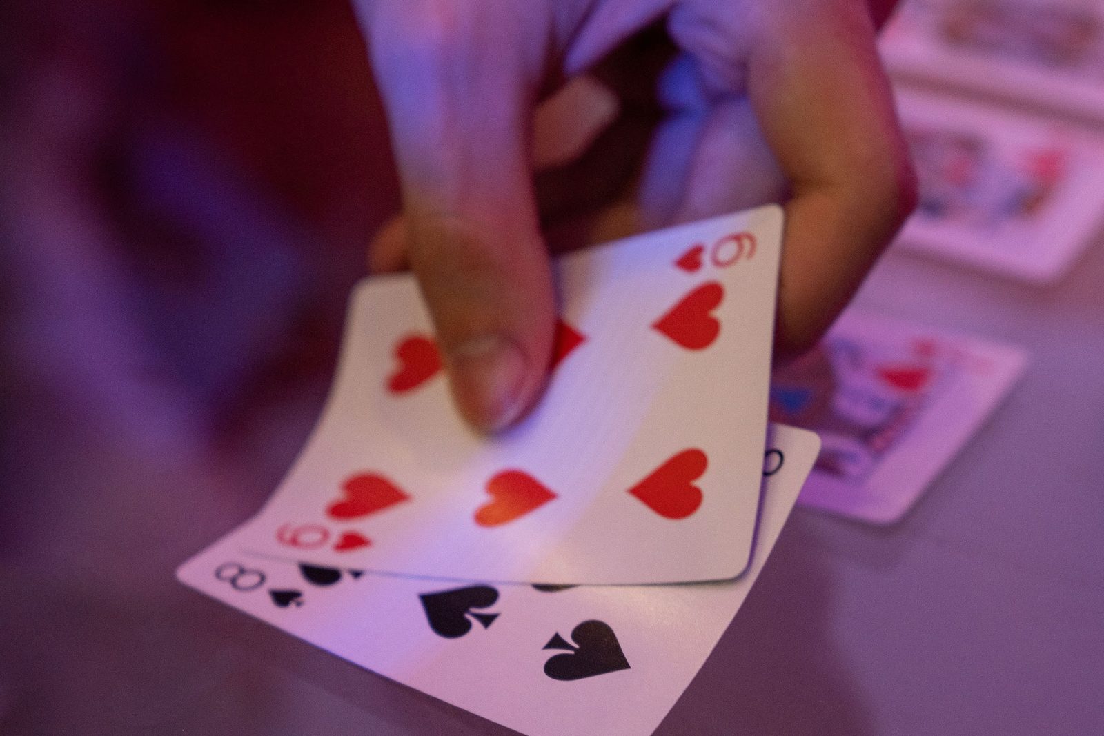 Playing cards fanned in one hand under violet light