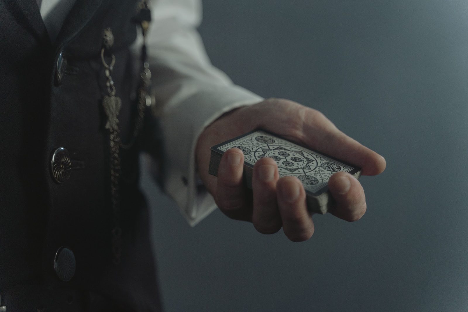 A magician's hand offering a deck of cards
