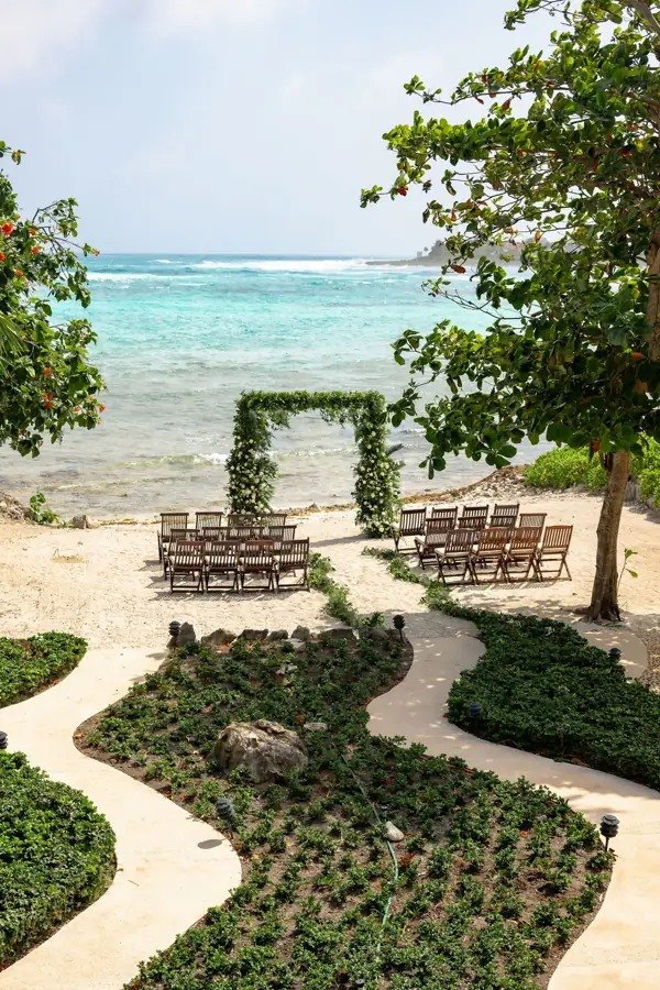 Ceremony set up on the beach, with rows of chairs and a floral arch