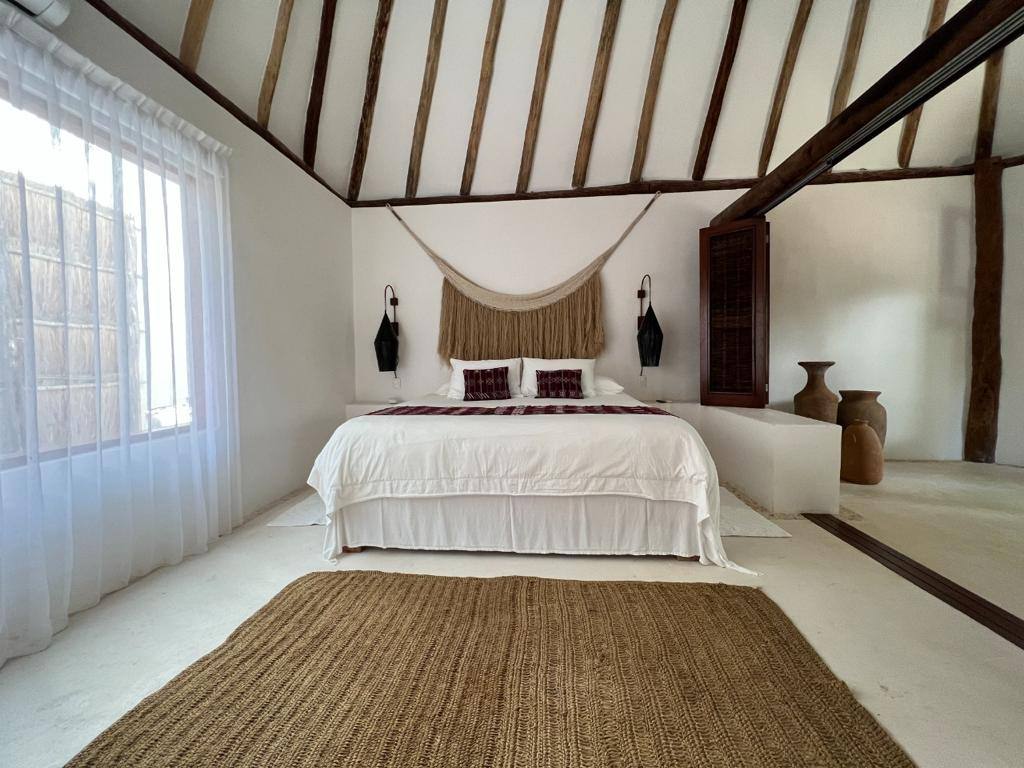 A white bedroom with a woven rug