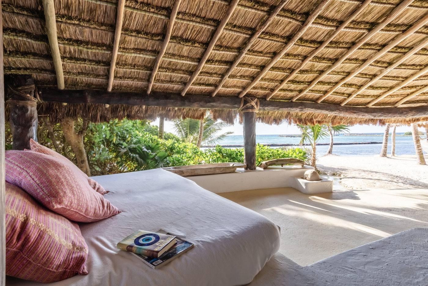 A daybed under the palapa facing the garden and sea