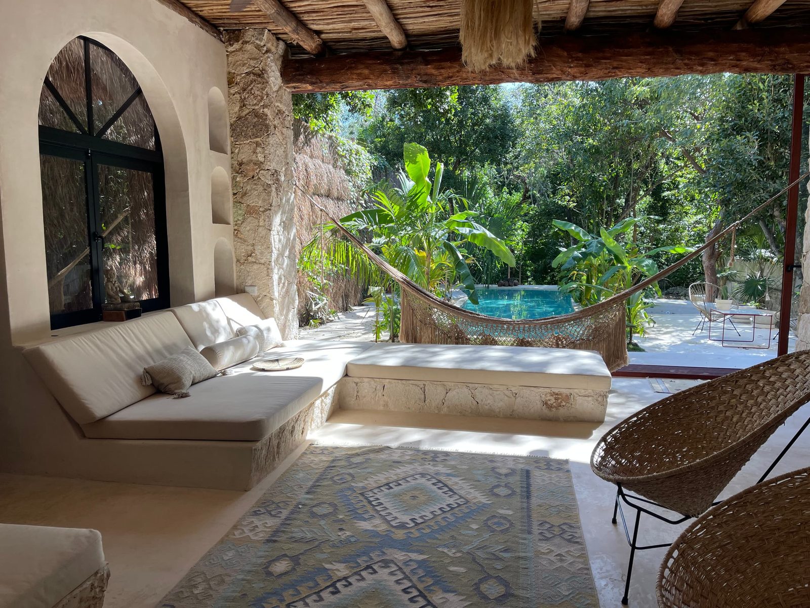The palapa living area with a hammock, opening to the pool