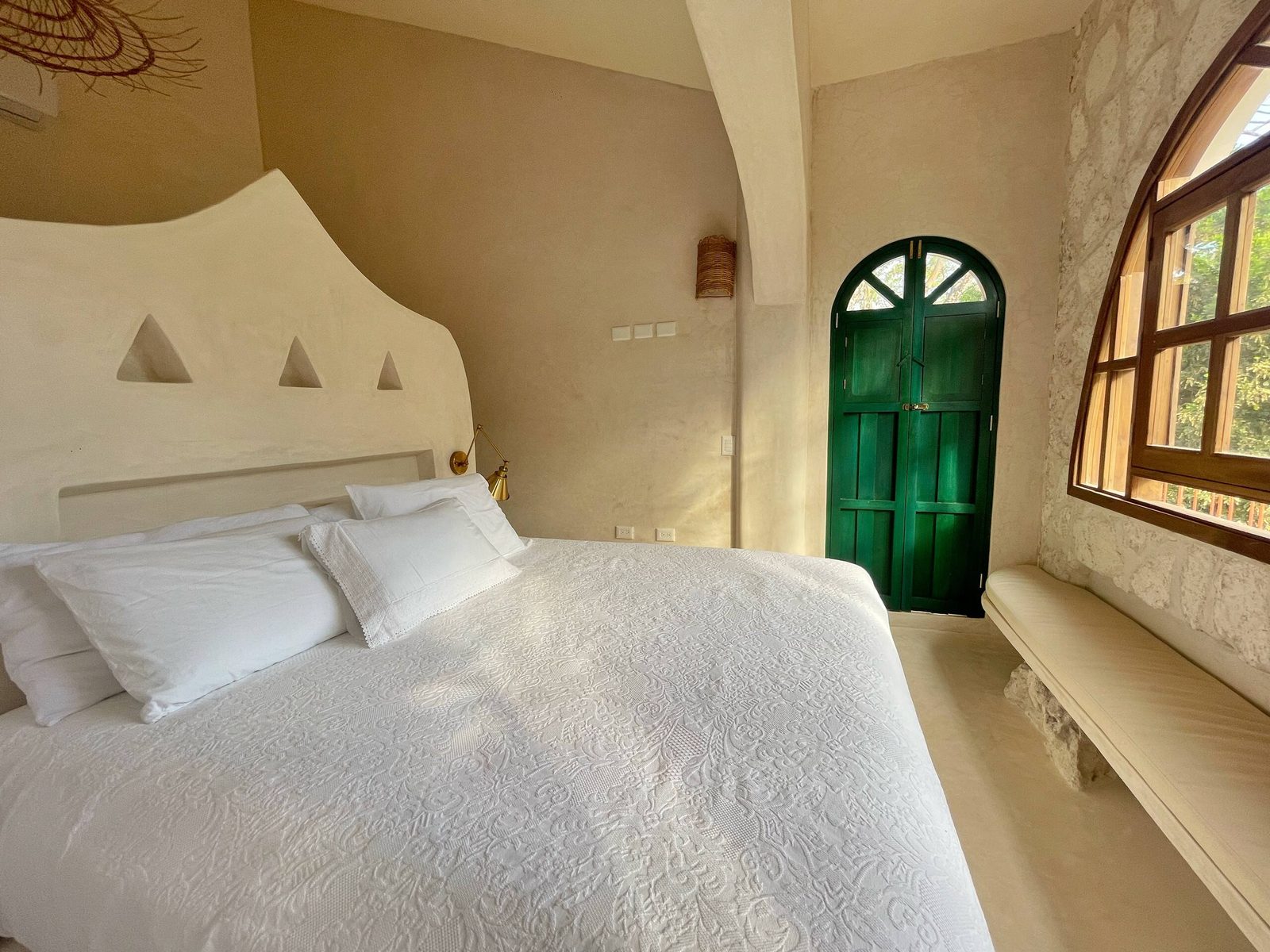 A bedroom with a green arched door and a garden window