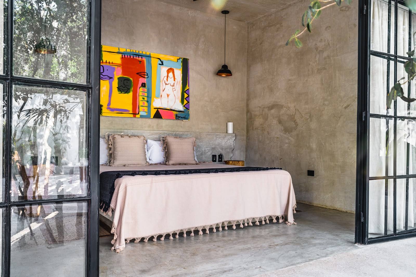 A bedroom with a colorful painting above the bed