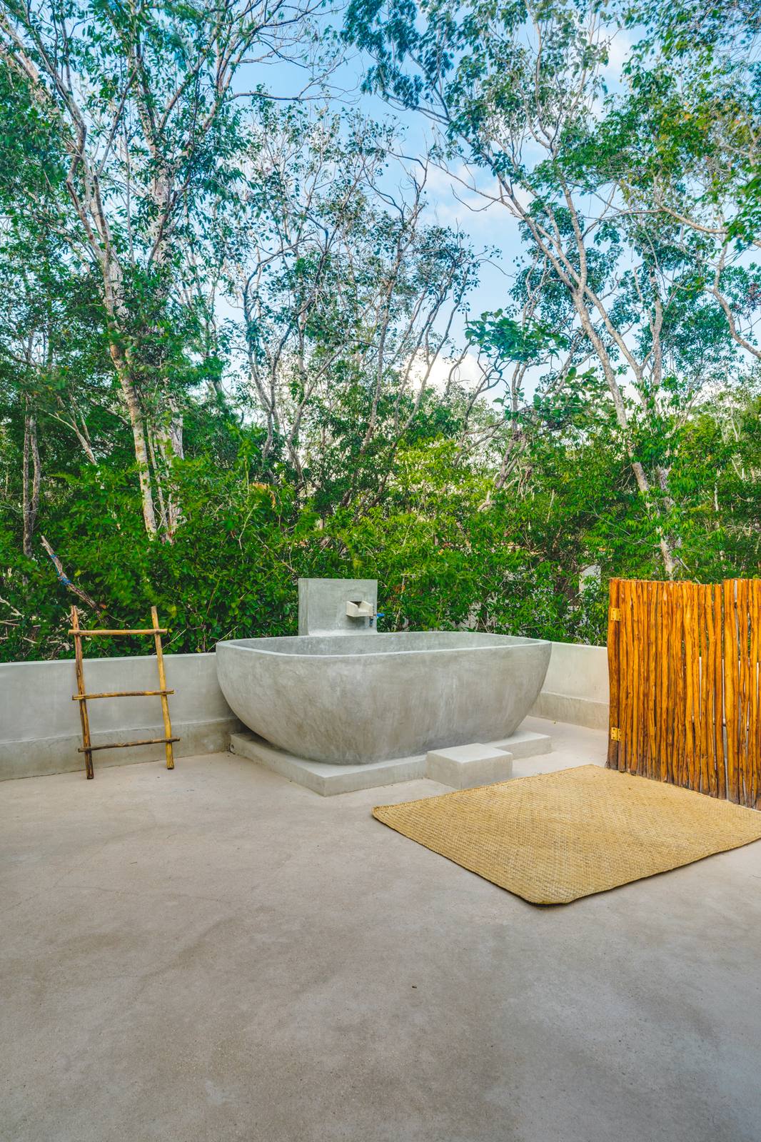 A freestanding bathtub on a private terrace among the trees