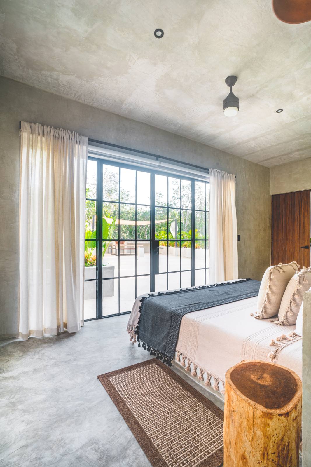 A bedroom with linen curtains and garden views
