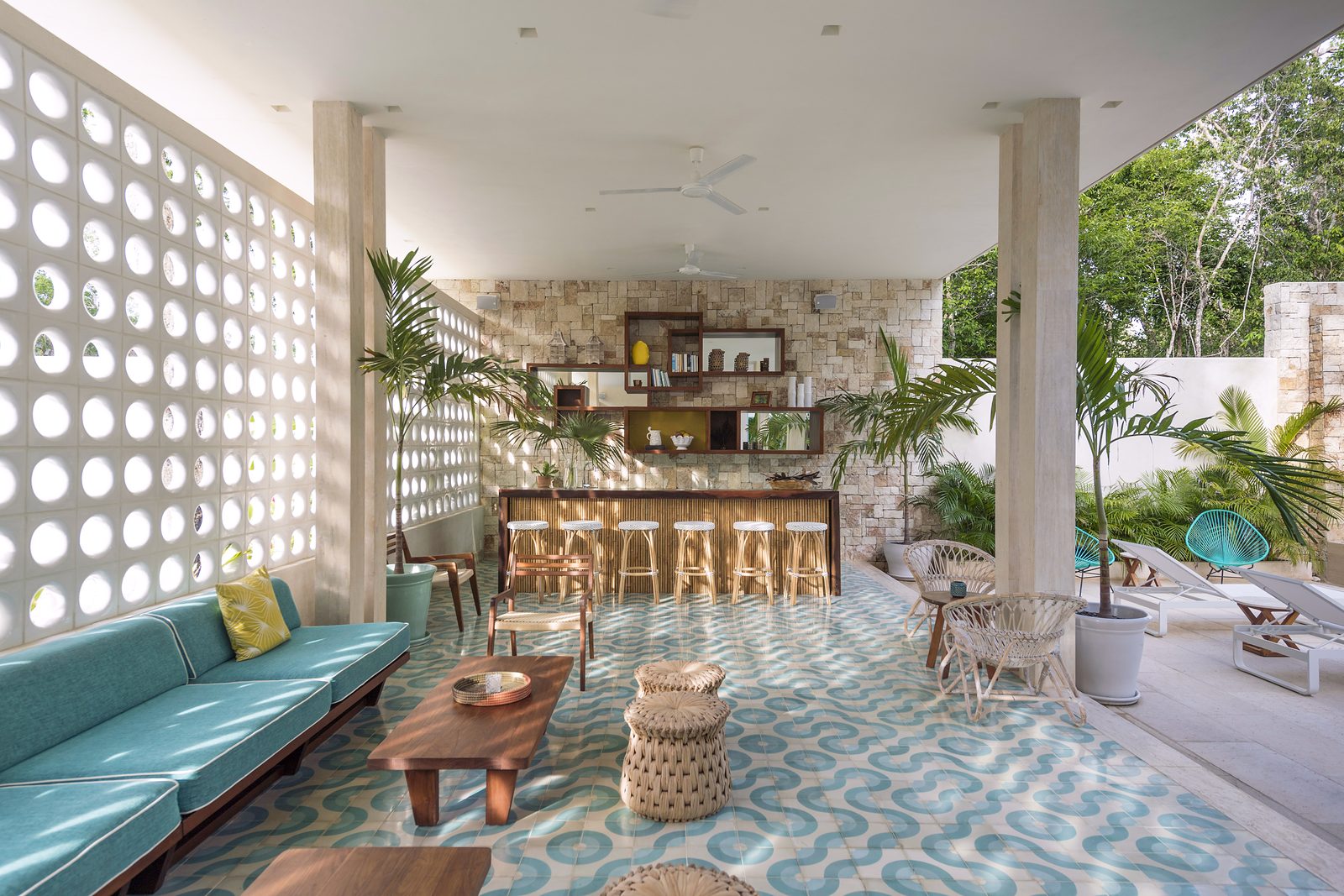 The open lounge and bar behind a wall of round breeze blocks, with turquoise sofas and patterned tiles