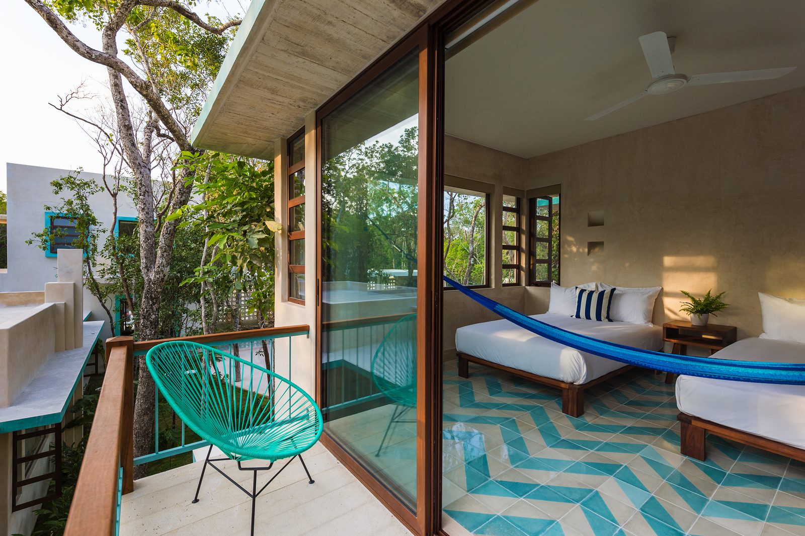 A bedroom with a hammock and sliding doors to a balcony over the garden