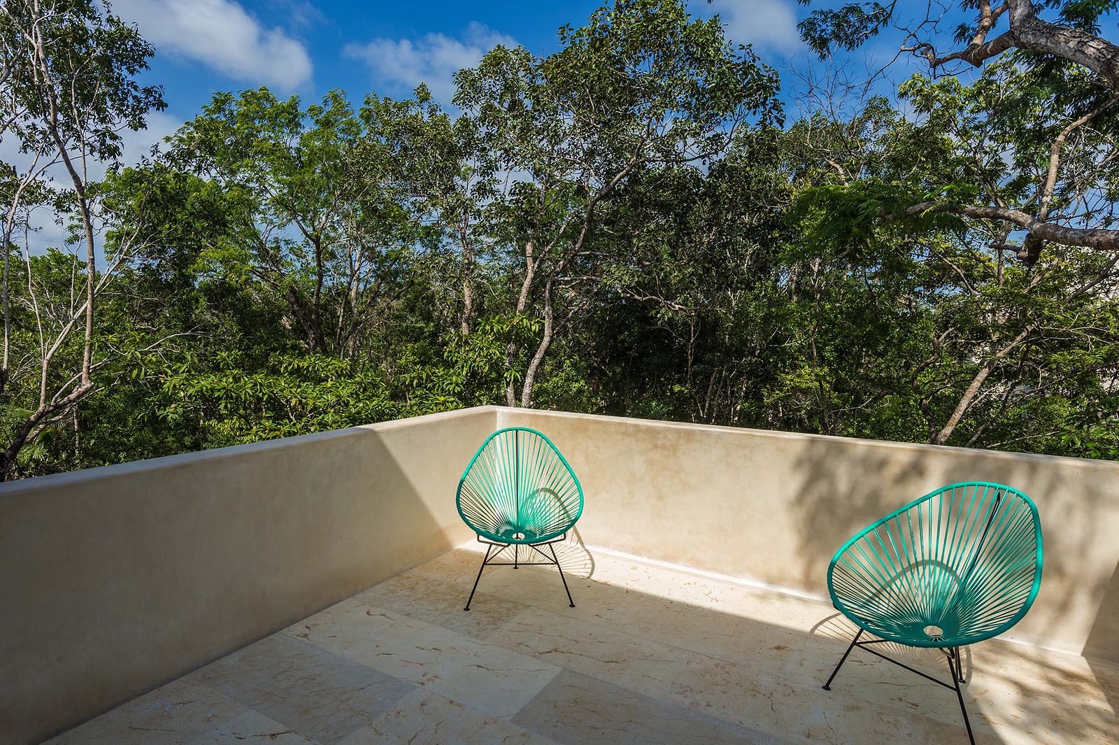 A private terrace with turquoise chairs above the treetops