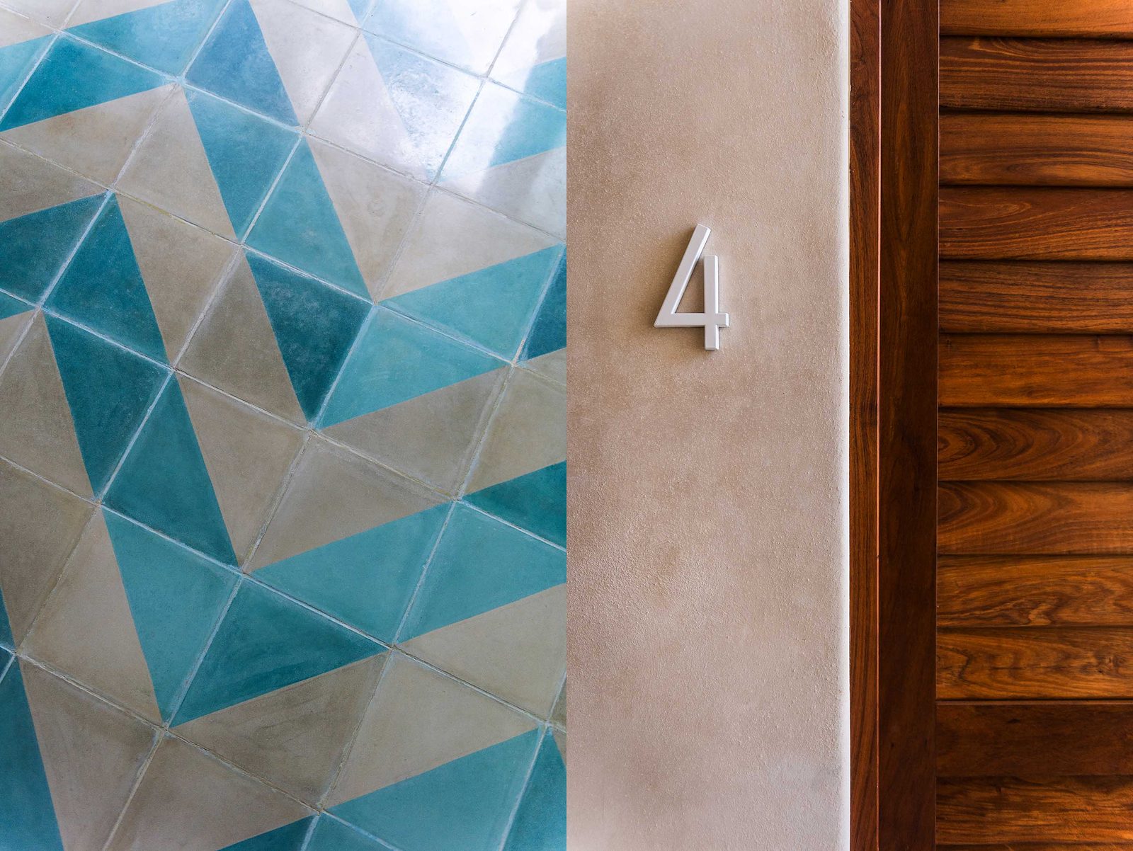 A turquoise tile floor, a room number and a louvered wooden door