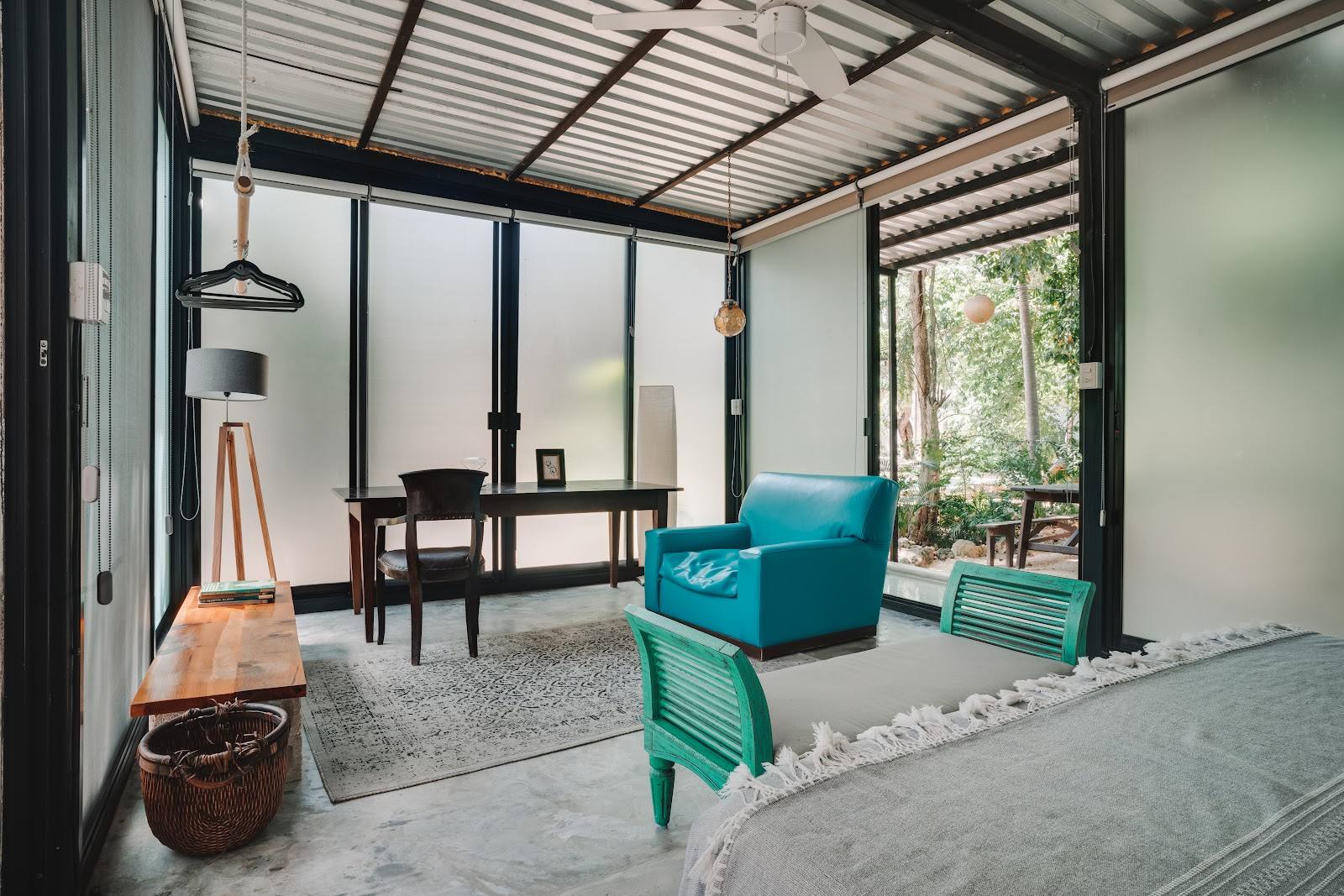 A bedroom with a desk and a turquoise armchair